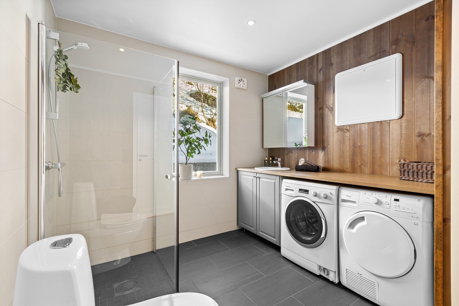 Praktisk baderom rett ved stuen med opplegg for vaskemaskin og god plass til oppbevaring Galleribilde