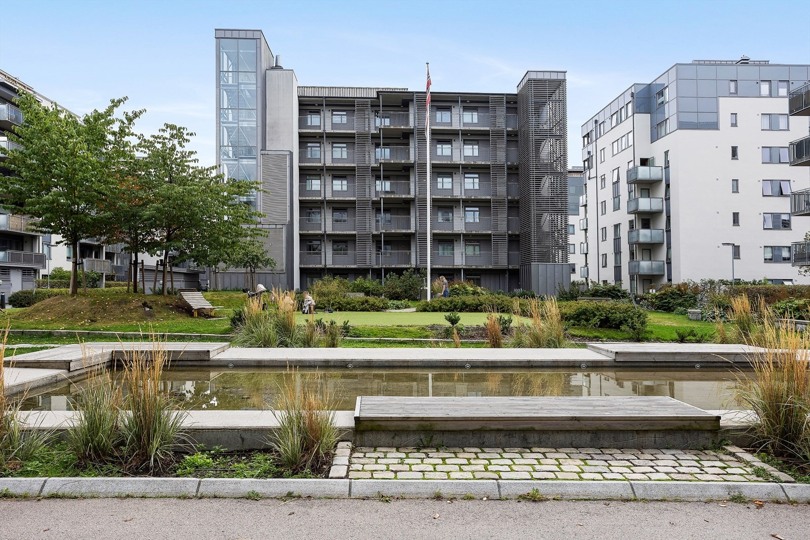 Velstelt gårdsrom med grøntarealer, vannspeil og moderne arkitektur - et rolig pusterom midt på Grünerløkka. Galleribilde