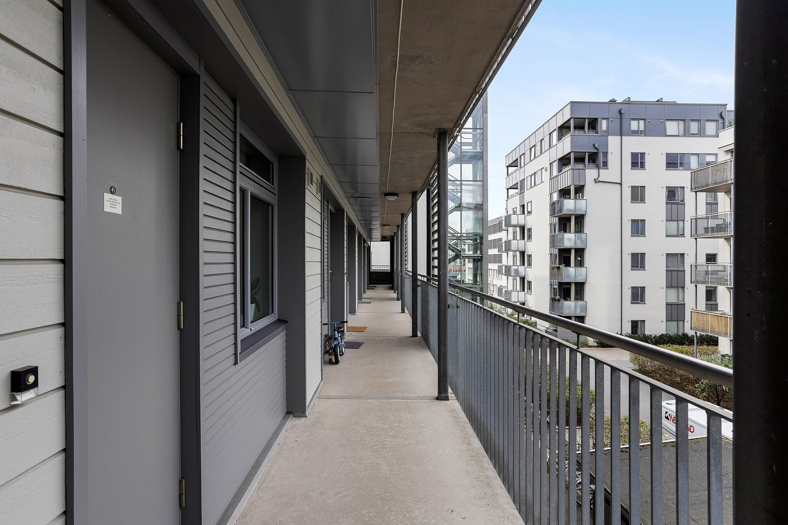 Velkommen inn - inngang fra skjermet svalgang med utsikt mot moderne gårdsrom. Galleribilde