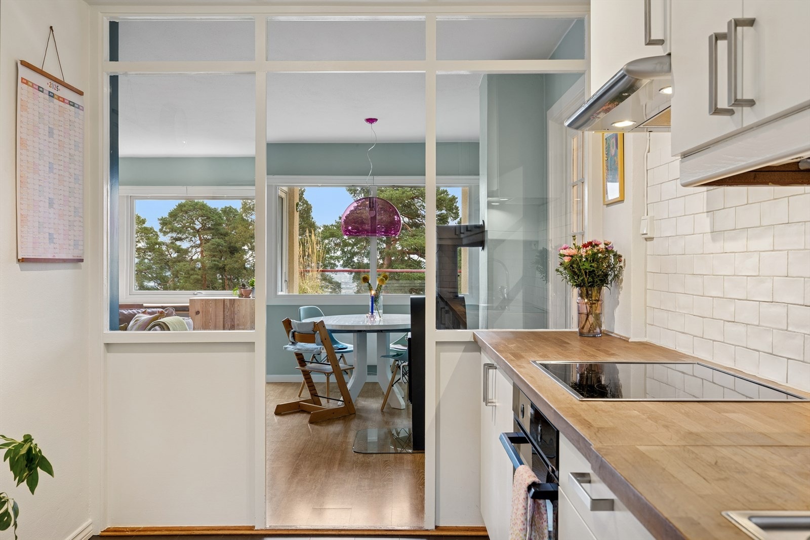 Kjøkkenet har en åpning mot stuen, rammet inn av vinduer som skaper en visuell forbindelse mellom rommene. Galleribilde