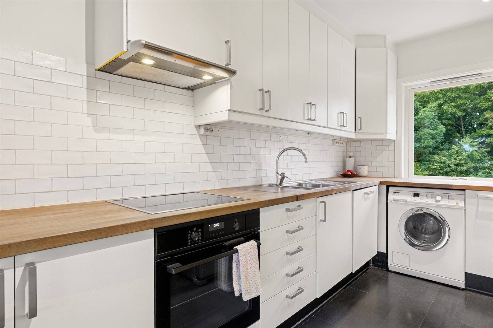 Praktisk kjøkken med integrert induksjonsplatetopp, stekeovn og oppvaskmaskin. Ellers er det frittstående kjøleskap og vaskemaskin. Galleribilde