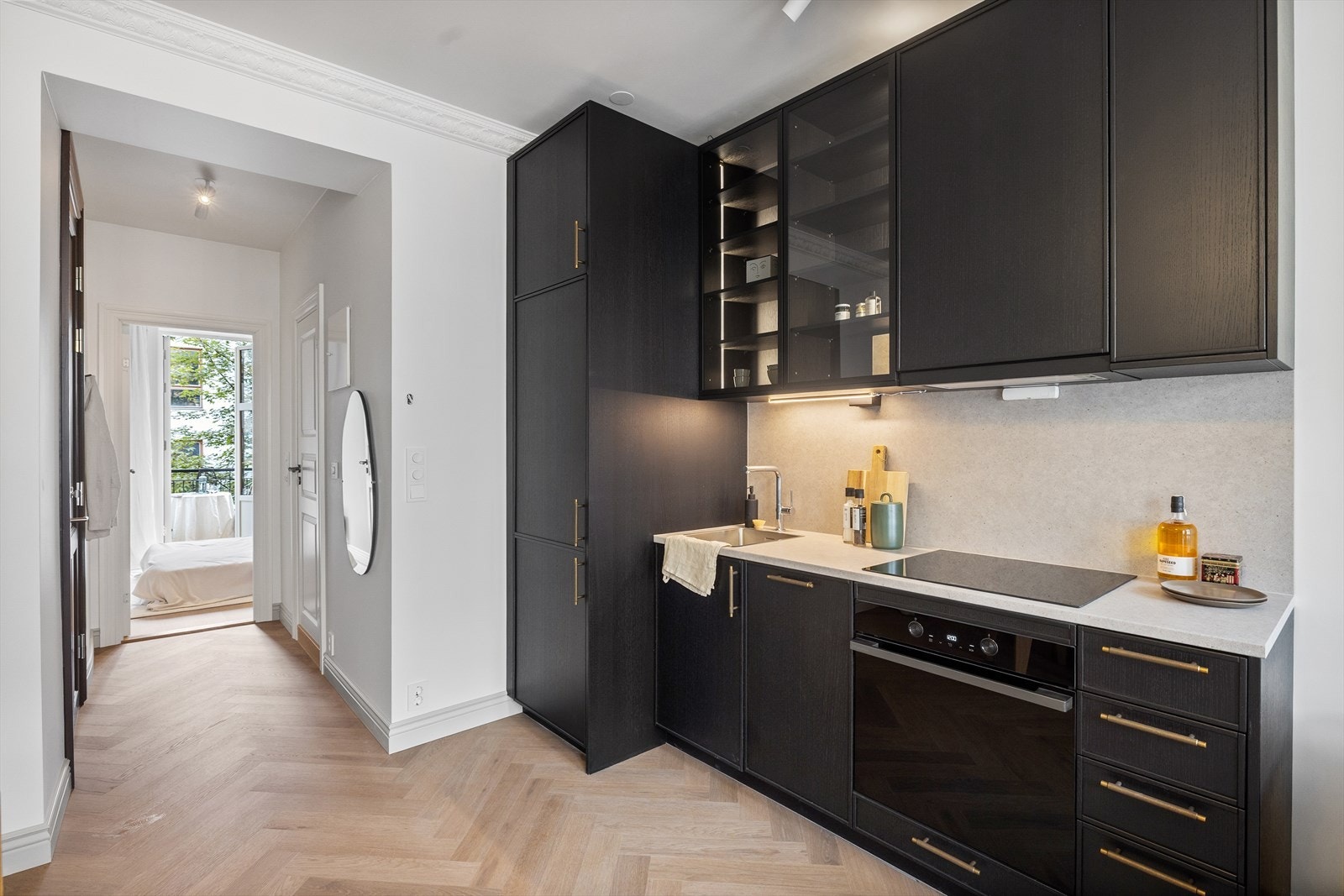 Kjøkkeninnredning har beiset fronter, laminat benkeplate, oppvaskkum i stål og kjøkkenplate over benk. Galleribilde