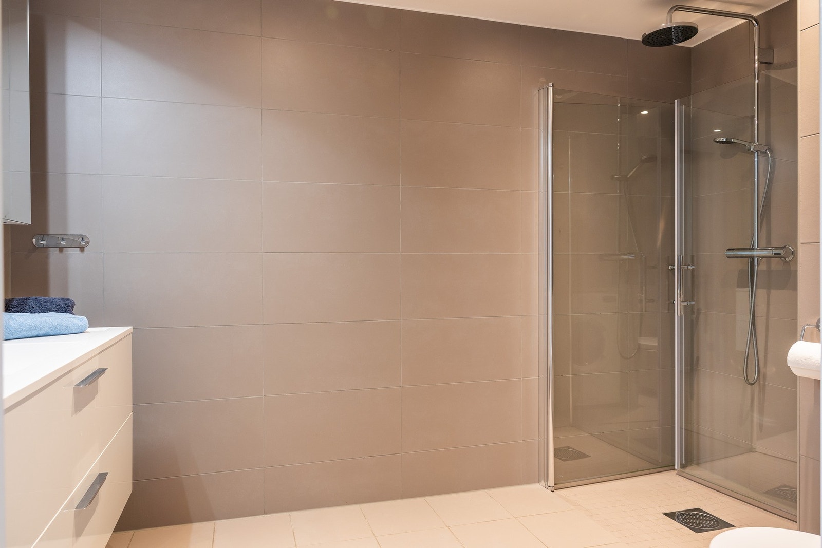 Delikat baderom med dusjnisje og innfellbare dusjdører, servant med ett greps blandebatteri og vegghengt toalett. Galleribilde