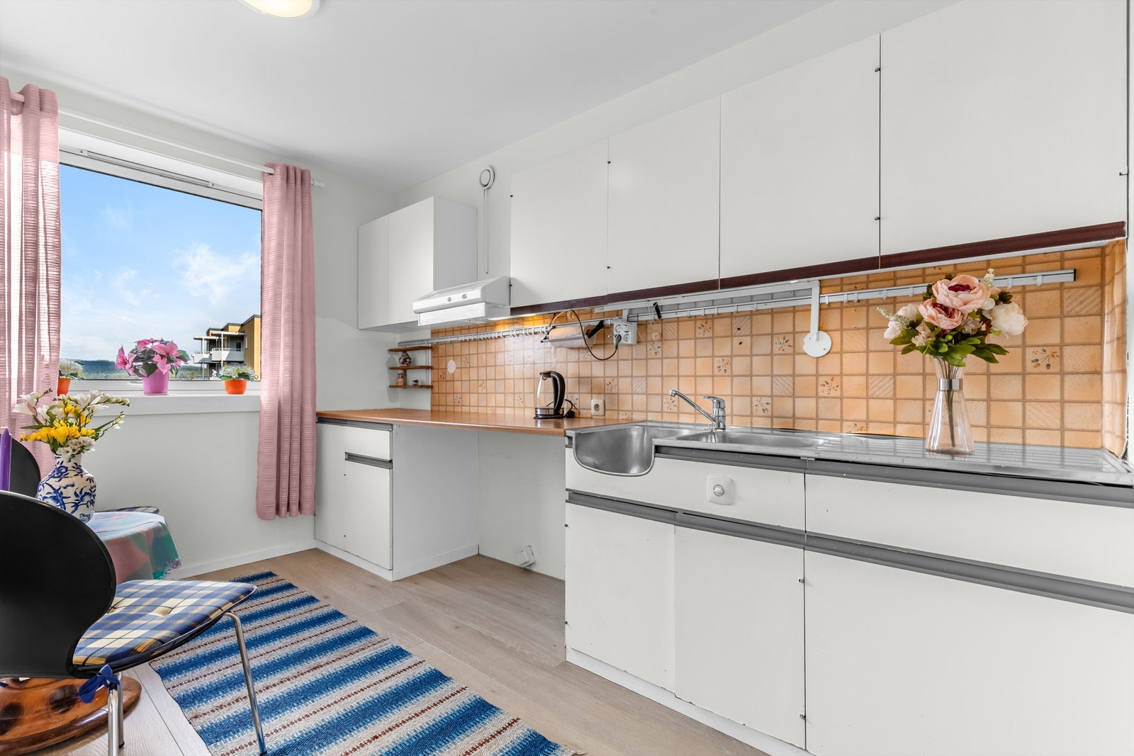 Kjøkken med praktisk innredning, laminat benkeplate og nedfelt oppvaskkum. Fliser over benk gir en klassisk og slitesterk løsning. Galleribilde
