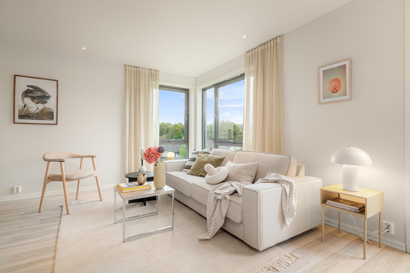 Innbydende sofahjørne med godt lysinnslipp og grønne omgivelser rett utenfor vinduene. Galleribilde