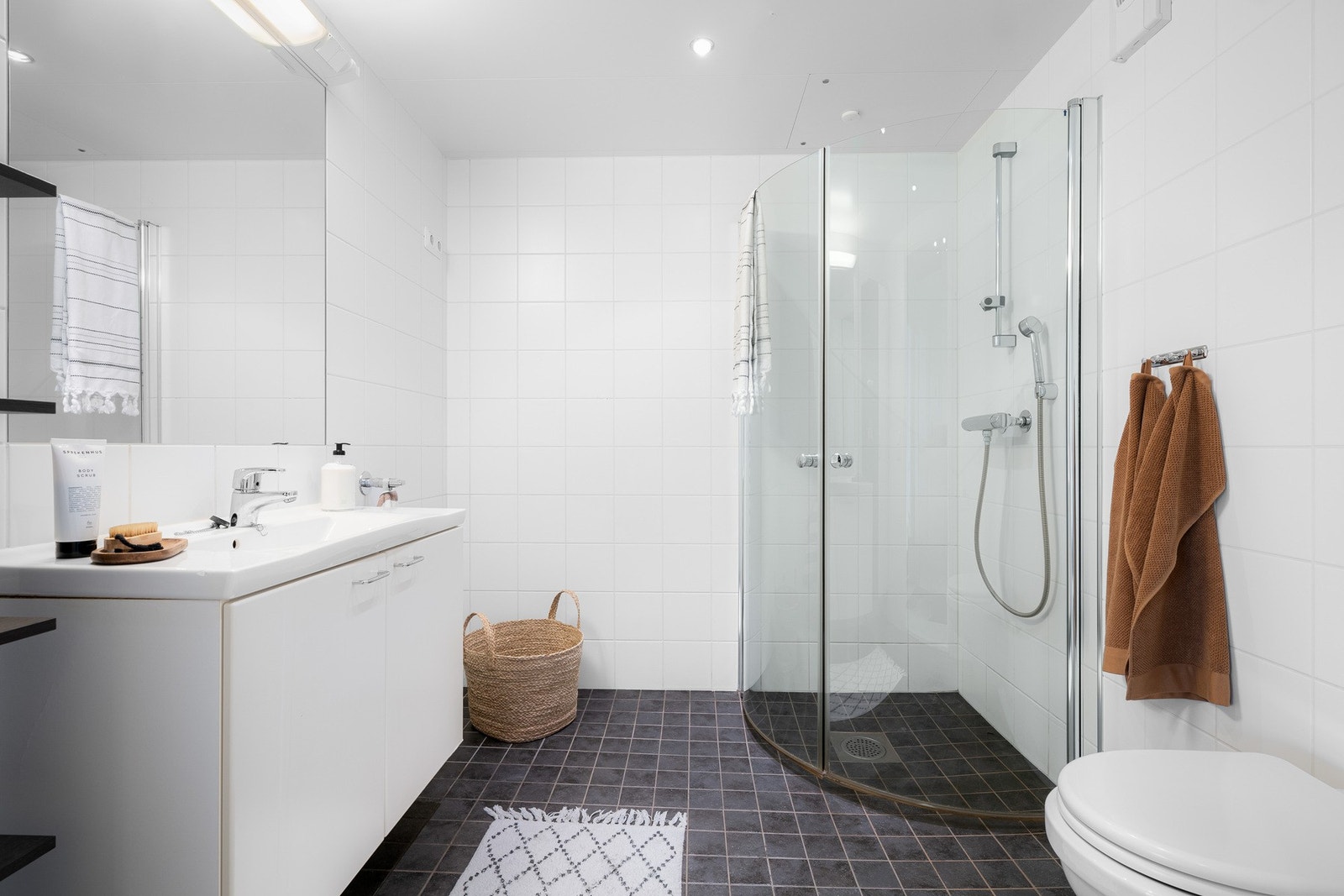 Romslig bad med veggmontert klosett og dusjhjørne med innfellbare glassdører. Galleribilde