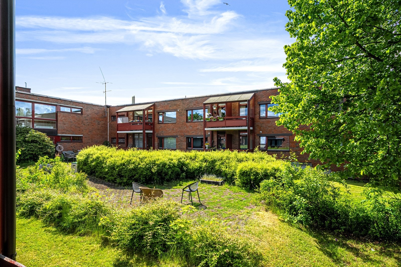 Stue med store vindusflater som gir både utsikt mot en frodig bakgård og en lys, åpen følelse - ideell for et trygt og rolig hjem. Galleribilde