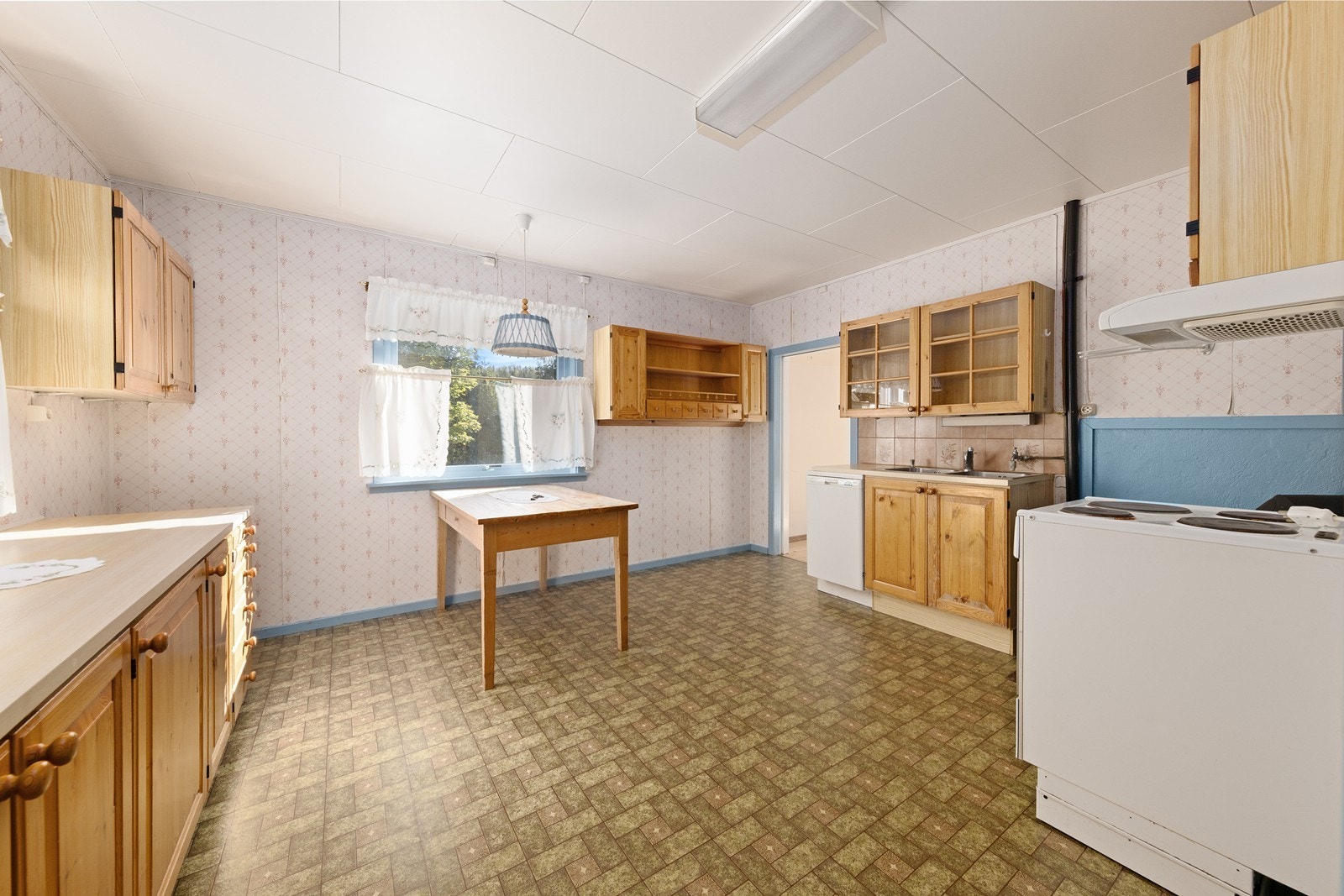 Kjøkkenet er innredet med profilerte og lakkerte fronter i furu, samt laminat benkeplater og nedfelt oppvaskkum i stål. Galleribilde