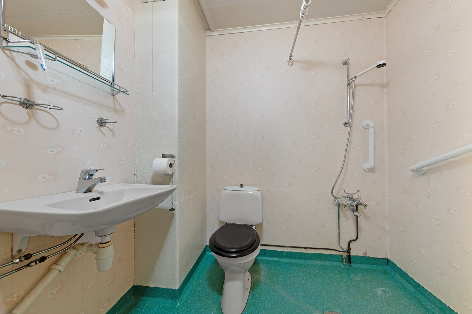 Badet er utstyrt med servant, frittstående toalett og åpen hjørnedusj. Rommet krever oppussing. Galleribilde