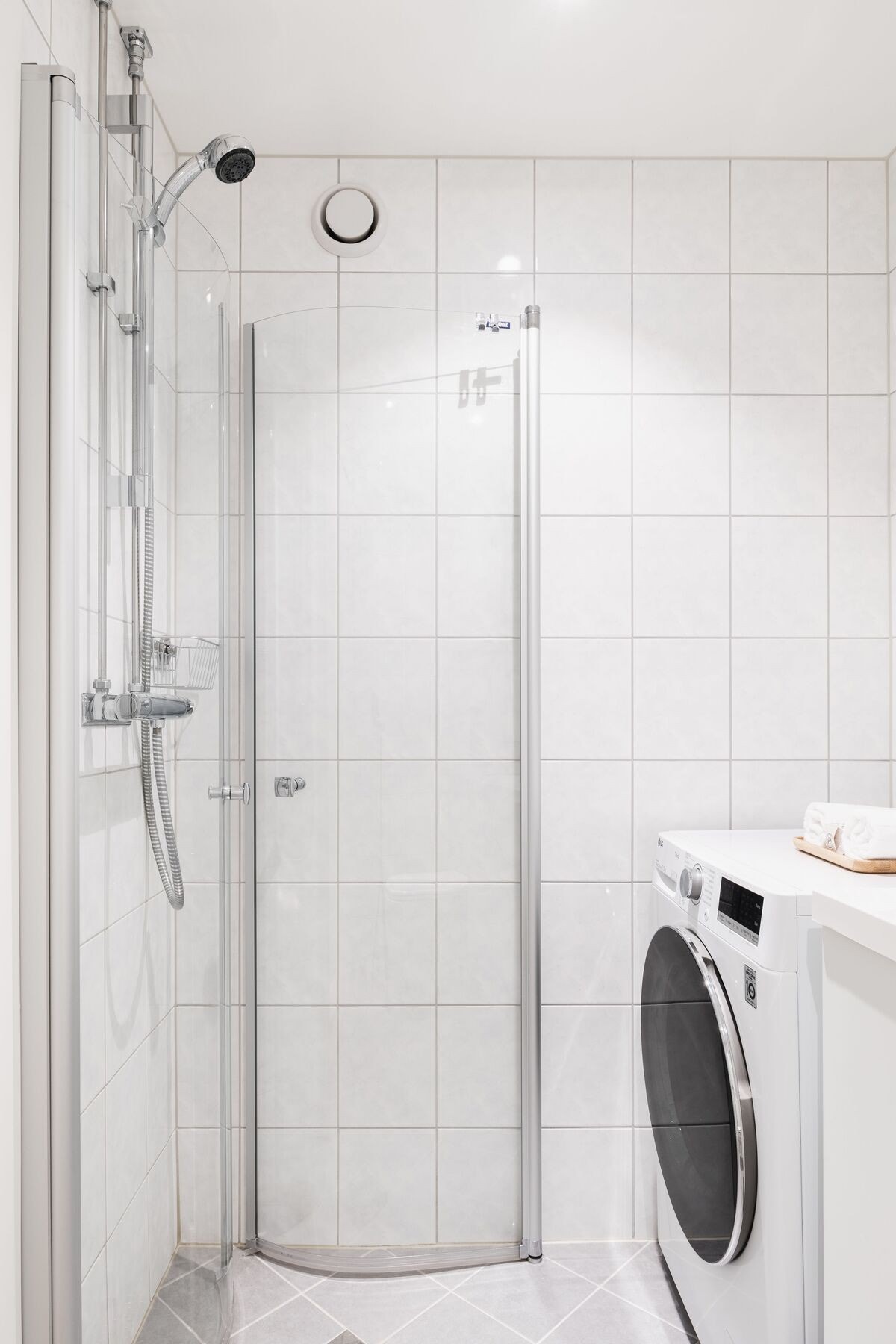 Baderom med vegghengt toalett med skjult sisterne, servant og dusj med svingbare dusjdører av herdet glass. Galleribilde