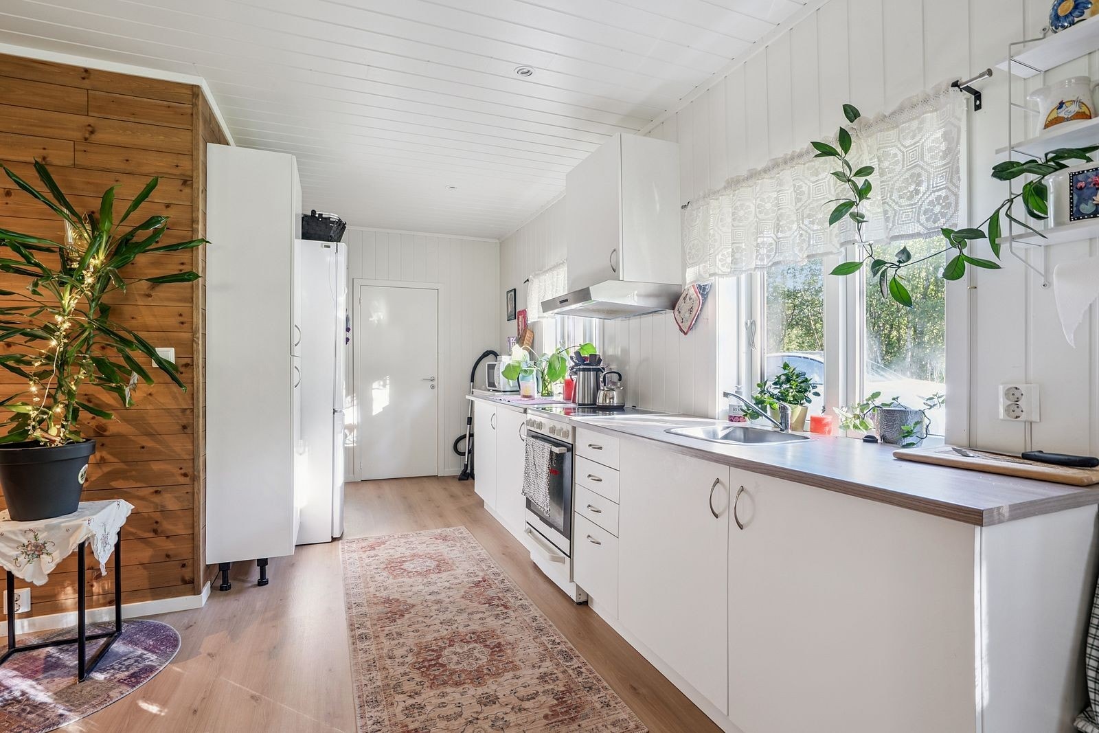 Lamgstrakt kjøkkenbenk med ekstra skap på motsatt side av benken - praktisk løsning. Vann i krane som kommer fra vanntank som er plassert ute sammen med pumpe. Varrmtvannstank i benk. Det er varmekabler på vannrørene utvendig. Galleribilde