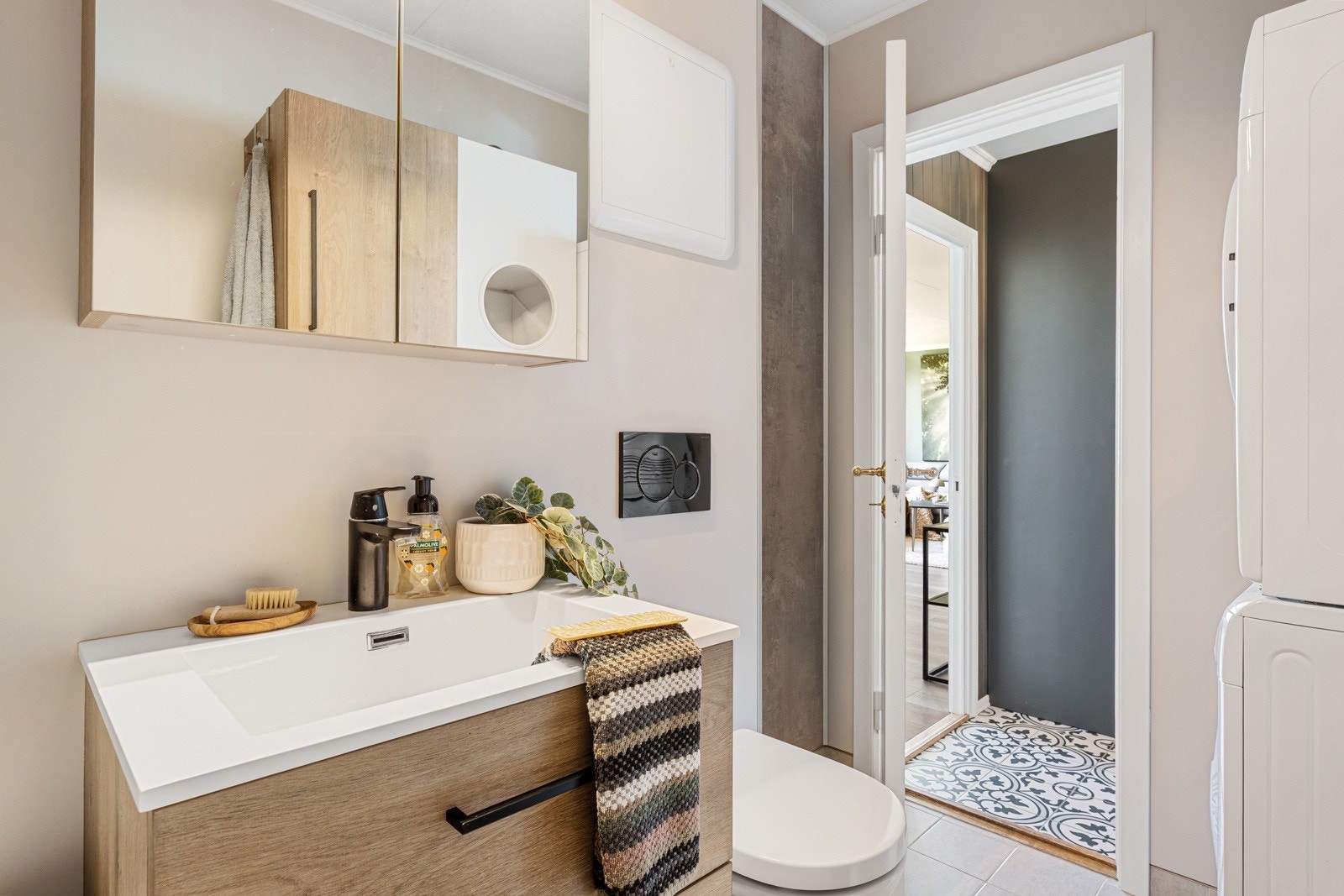 Innredet med servant med underskap, speilskap med lys, vegghengt toalett, badekar og opplegg for vaskemaskin. Galleribilde