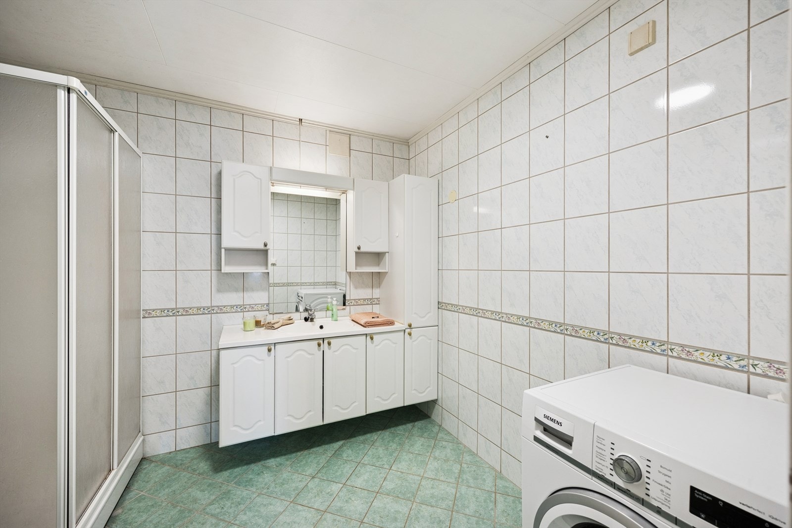 Badet er innredet med gulvstående toalett, dusjkabinett og nedfelt servant med underskap. Galleribilde