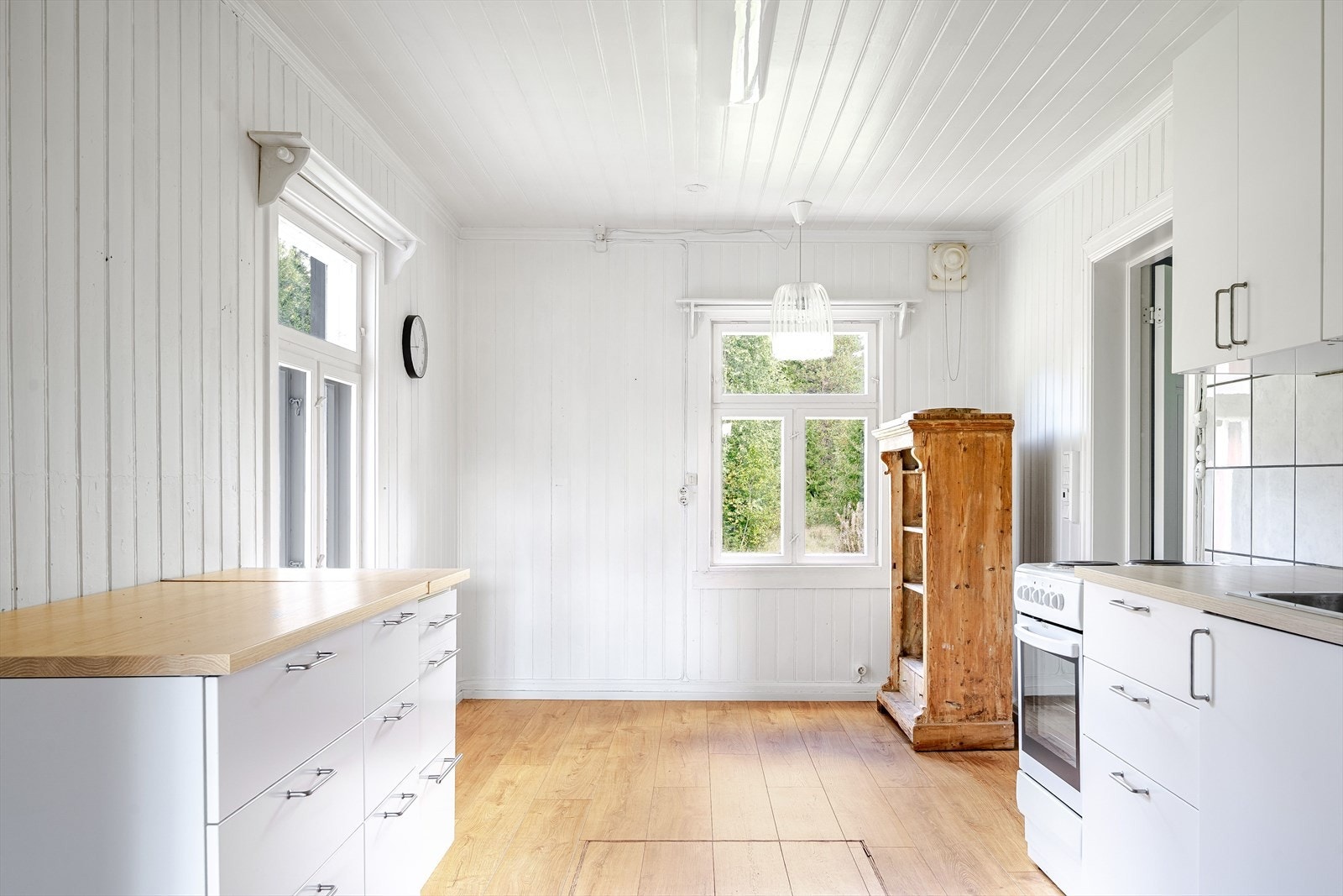Kjøkken opplyst fra 2019 med glatte fronter på over- og underskap, laminerte benkeplater og fliser i benkerygg. Plass for spisegruppe ved vinduet. Galleribilde
