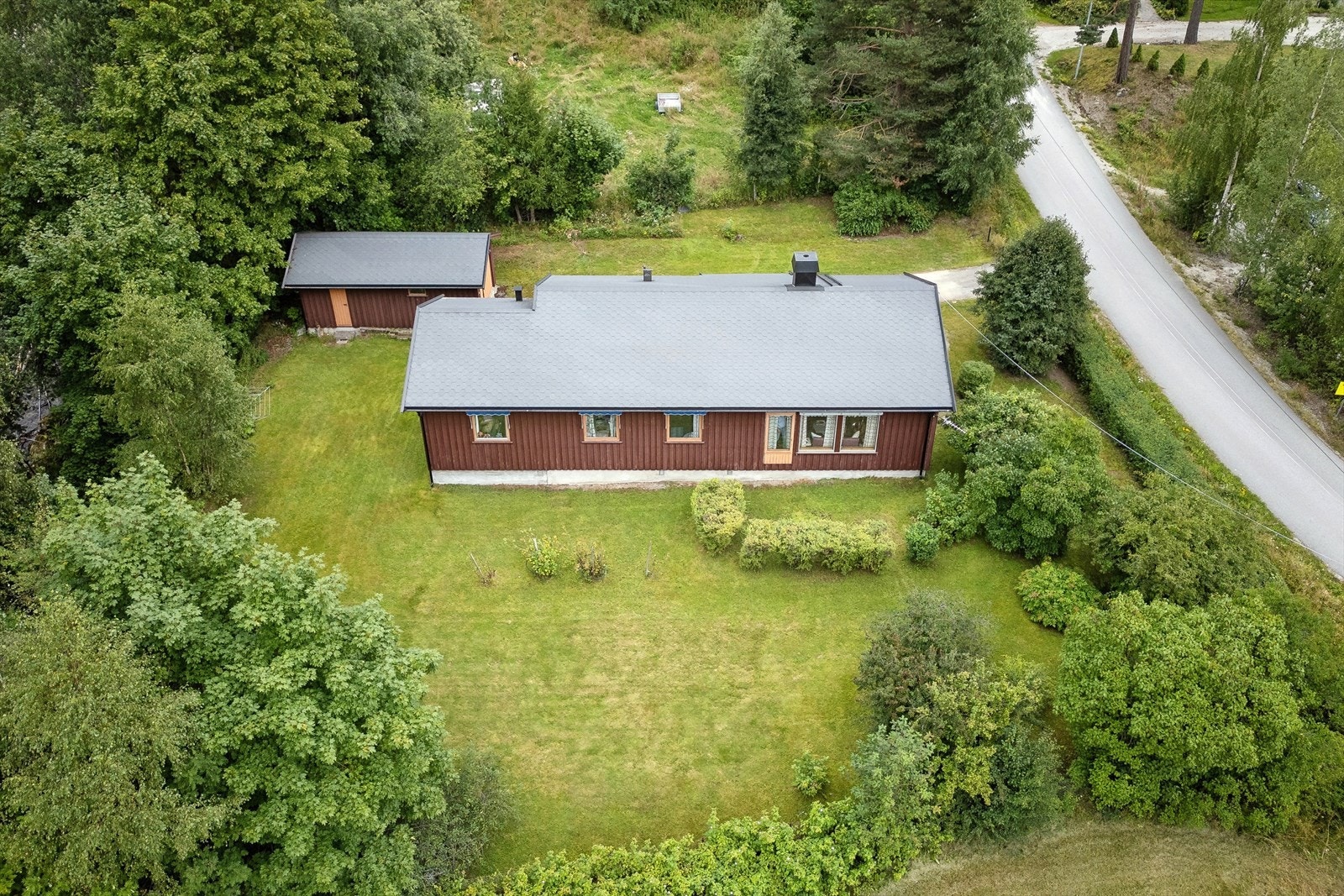 Tomten er tilnærmet flat, opparbeidet med store plenarealer, hekk, trær, samt noe beplantning med pryd- og bærbusker. Galleribilde