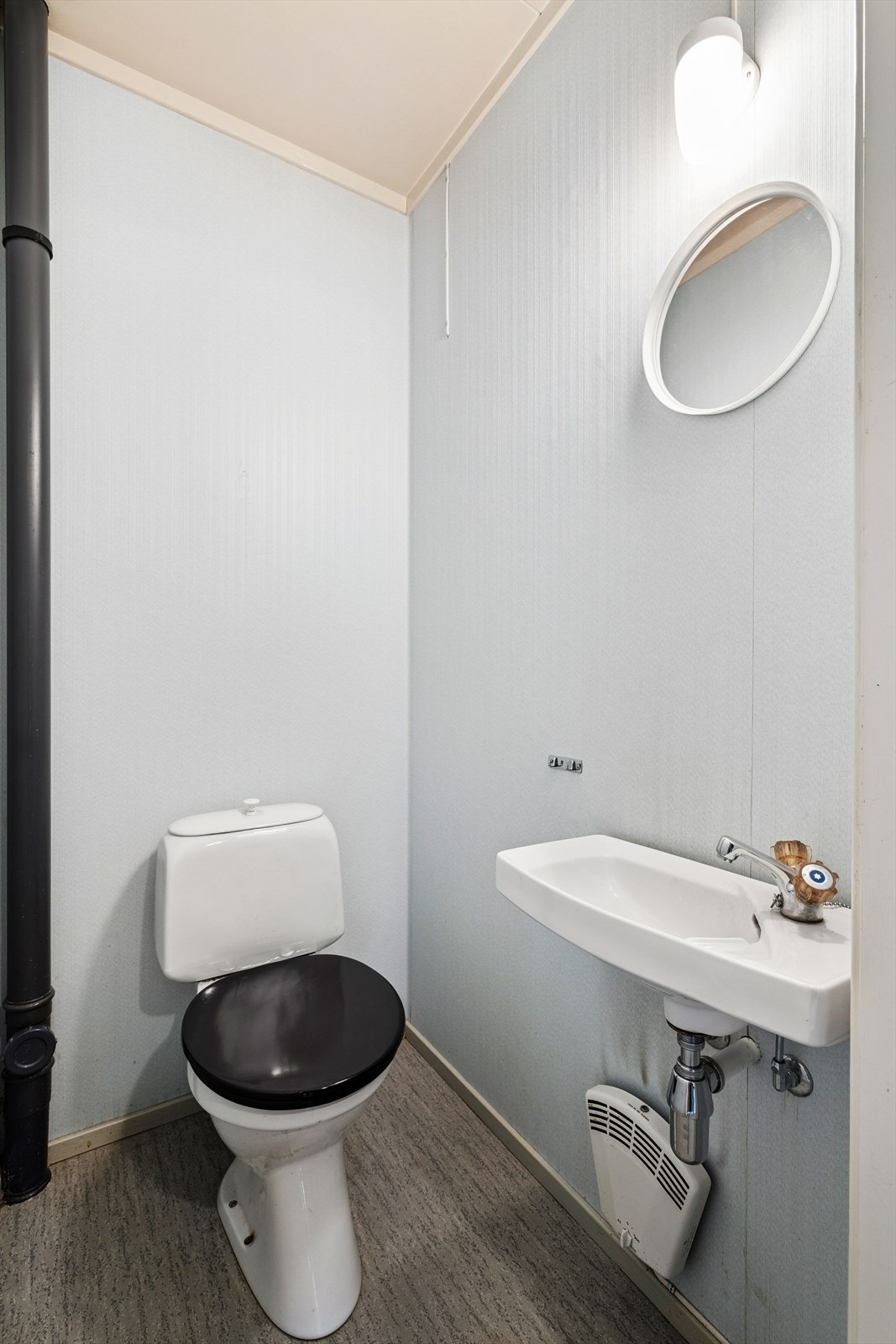 Toalettrom fra byggeår har belegg på gulv, tapet på innvendige vegger og malte plater i himling, utstyrt med toalett og liten vegghengt vask. Galleribilde
