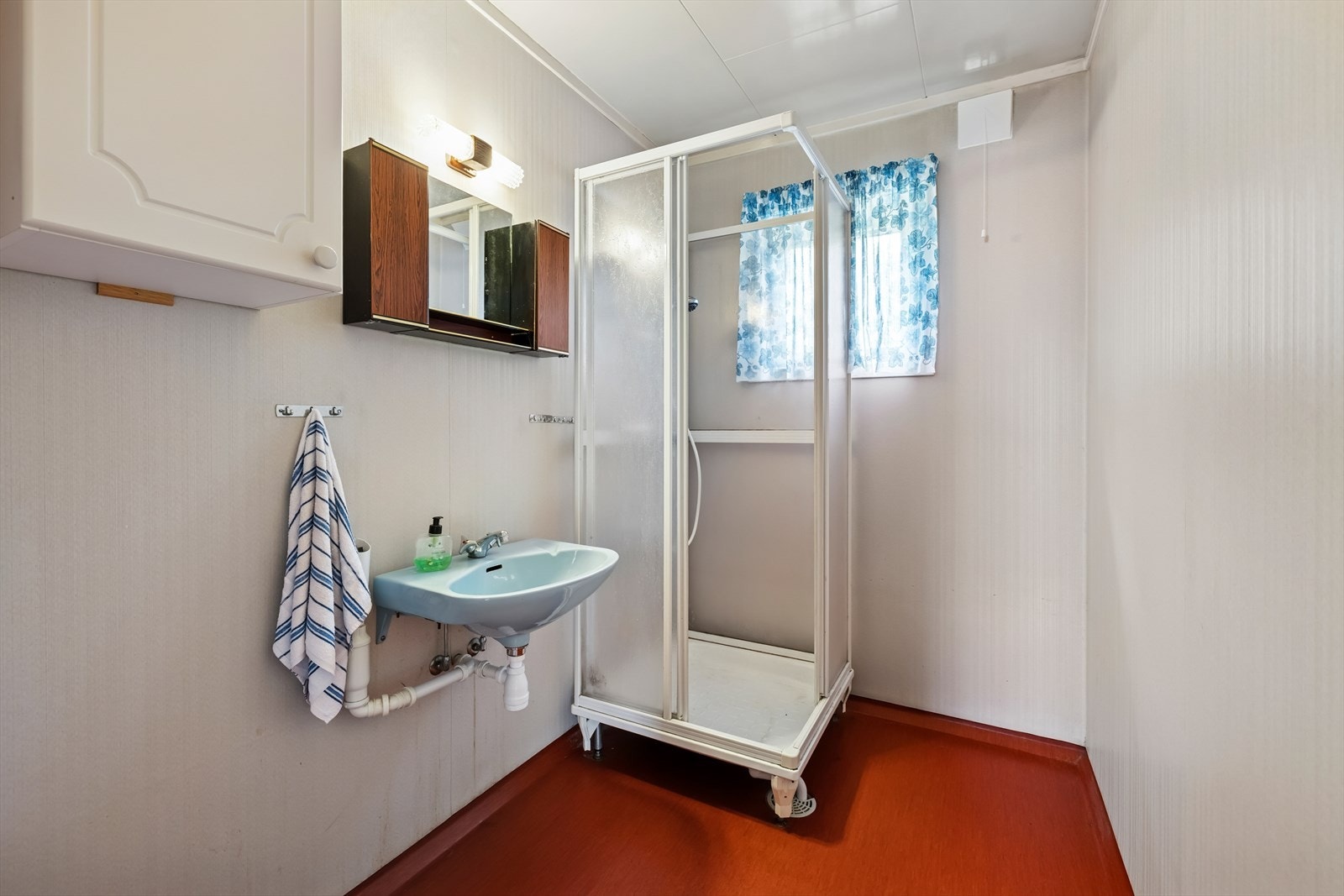 Baderom fra byggeåret med våtromsbelegg på gulv, våtromsplater på vegger, utstyrt med dusjkabinett, servant, veggskap, samt opplegg for vaskemaskin. Galleribilde