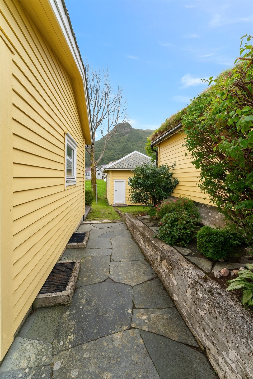 Uteområde med hage, terrasse, uthus, enkeltgarasje og dobbelgarasje. Galleribilde