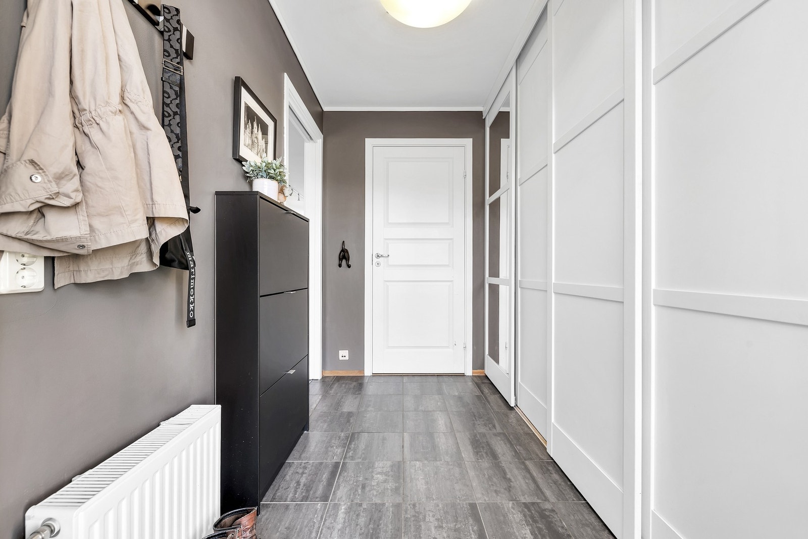 Romslig og flislagt inngangsparti med stor skyvedørsgarderobe. Galleribilde
