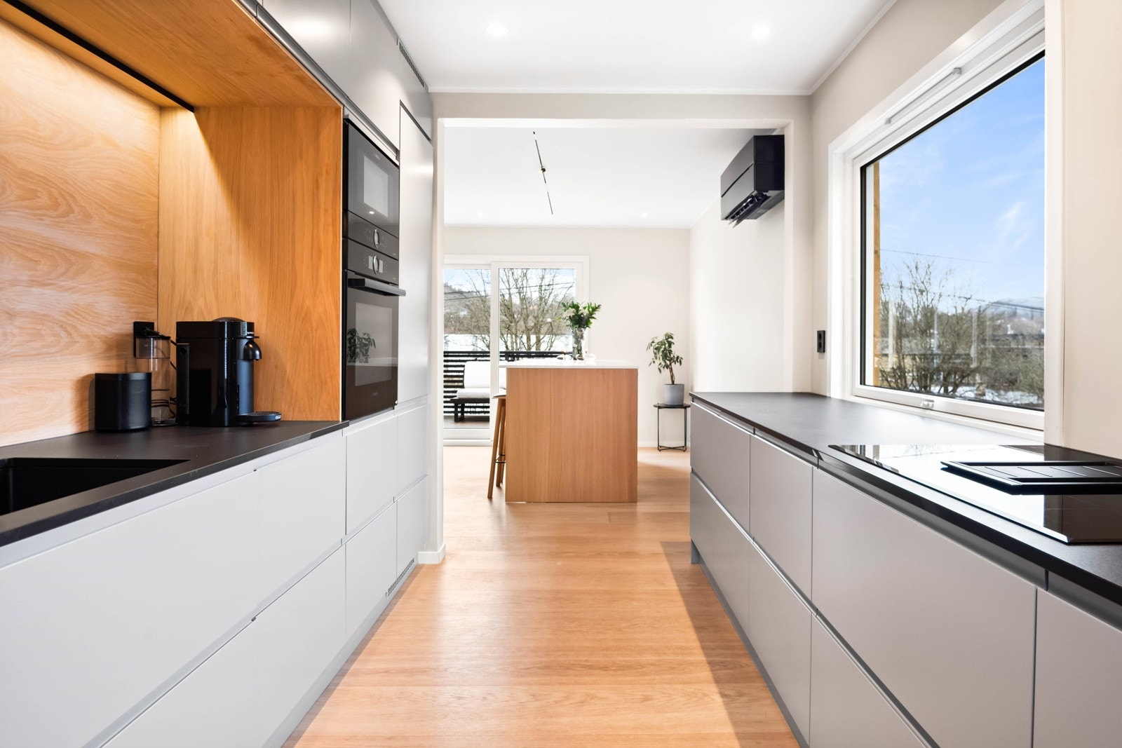 Lekkert kjøkken med glatte grå fronter og integrerte hvitevarer. Galleribilde