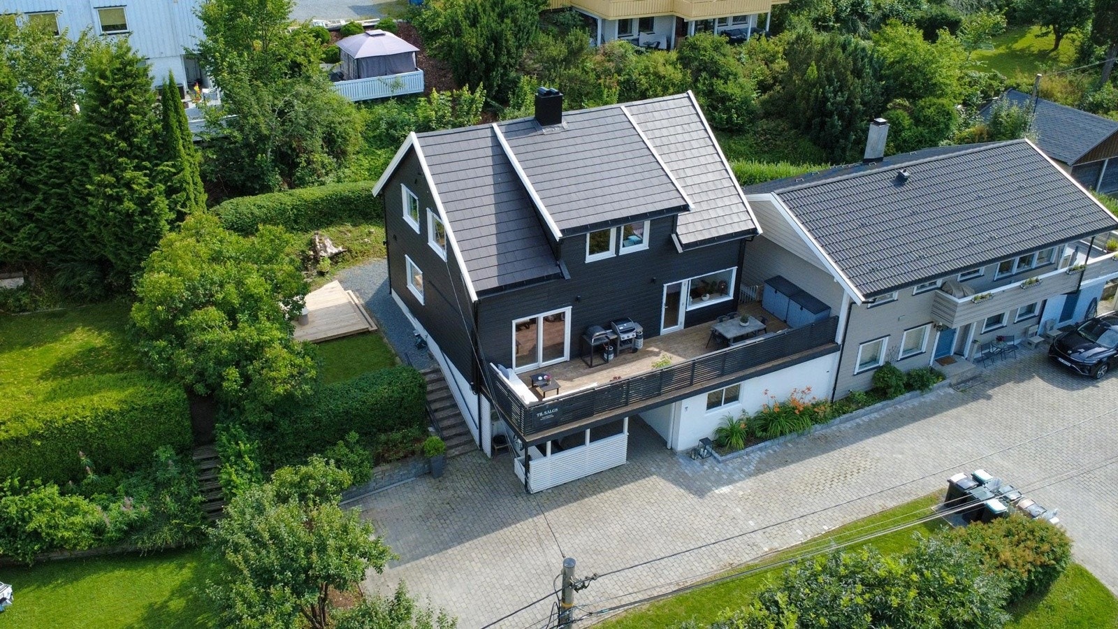 Eneboligen har en stor gårdsplass med flere biloppstillingsplasser Galleribilde