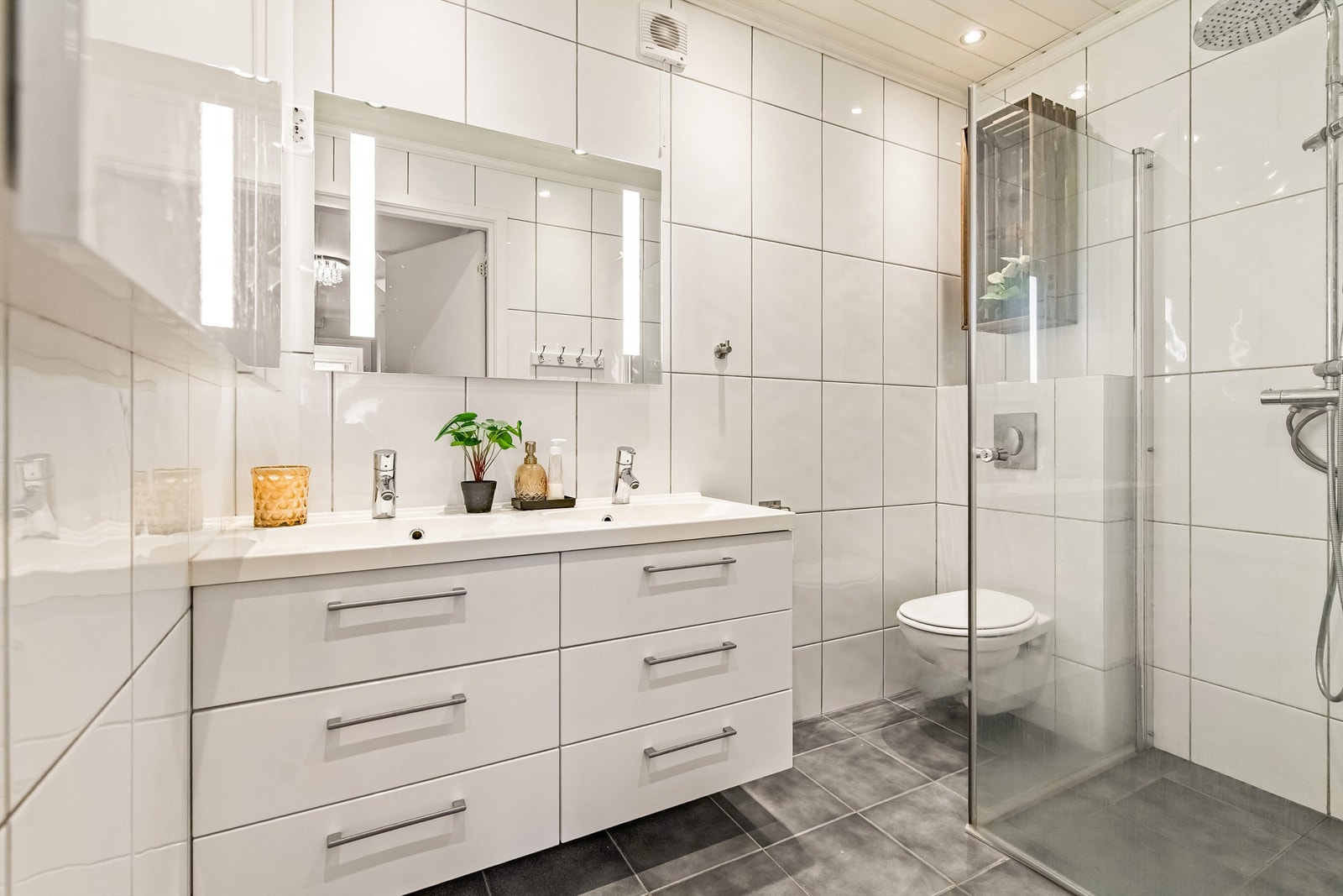 Delikat flislagt bad med dobbel vask i innredning, dusjnisje og wc Galleribilde