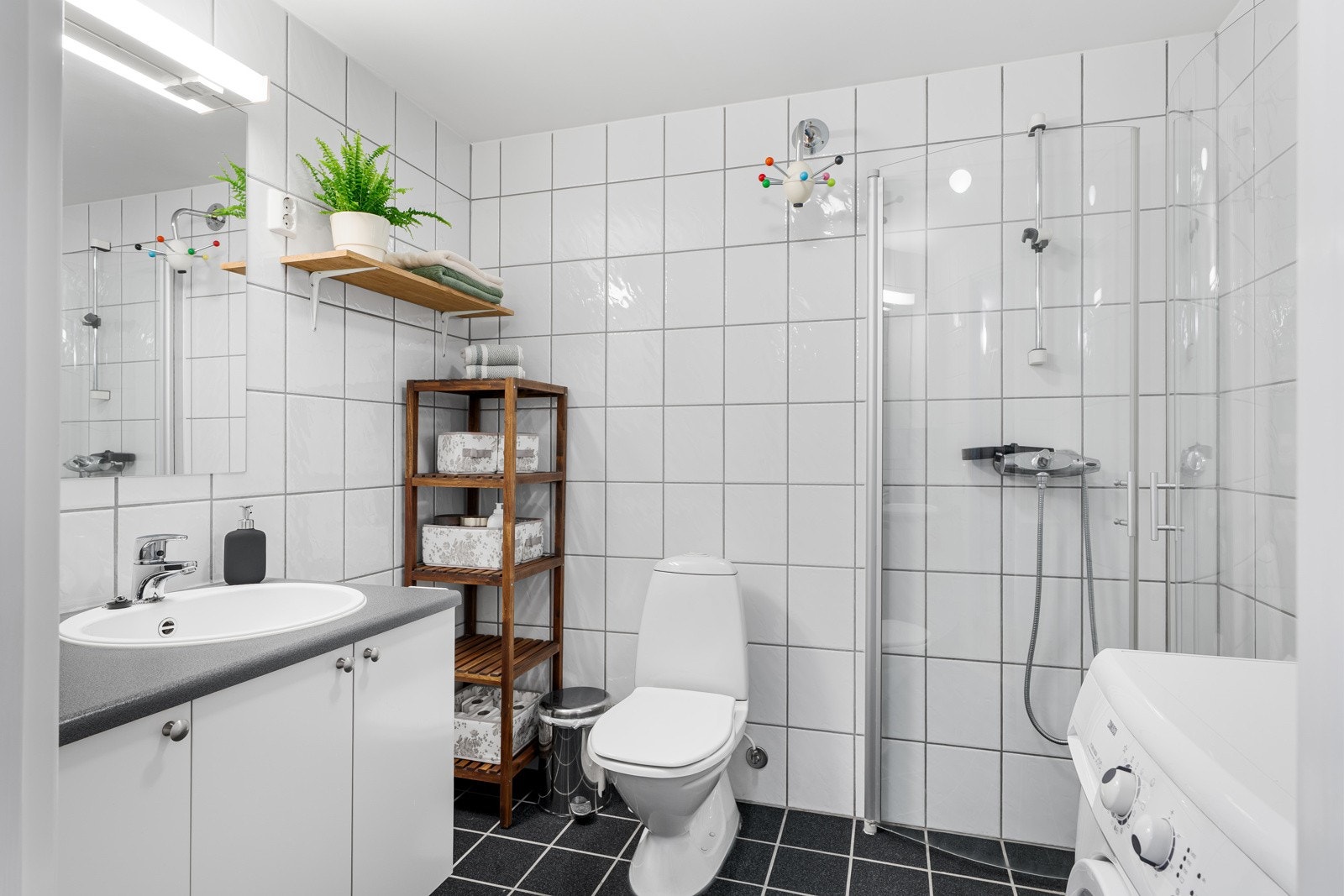 Badet oppleves lyst og innbydende, pent flislagt på vegger og gulv. Baderomsinnredningen har muligheter for lagringsplass i servantskap. Galleribilde