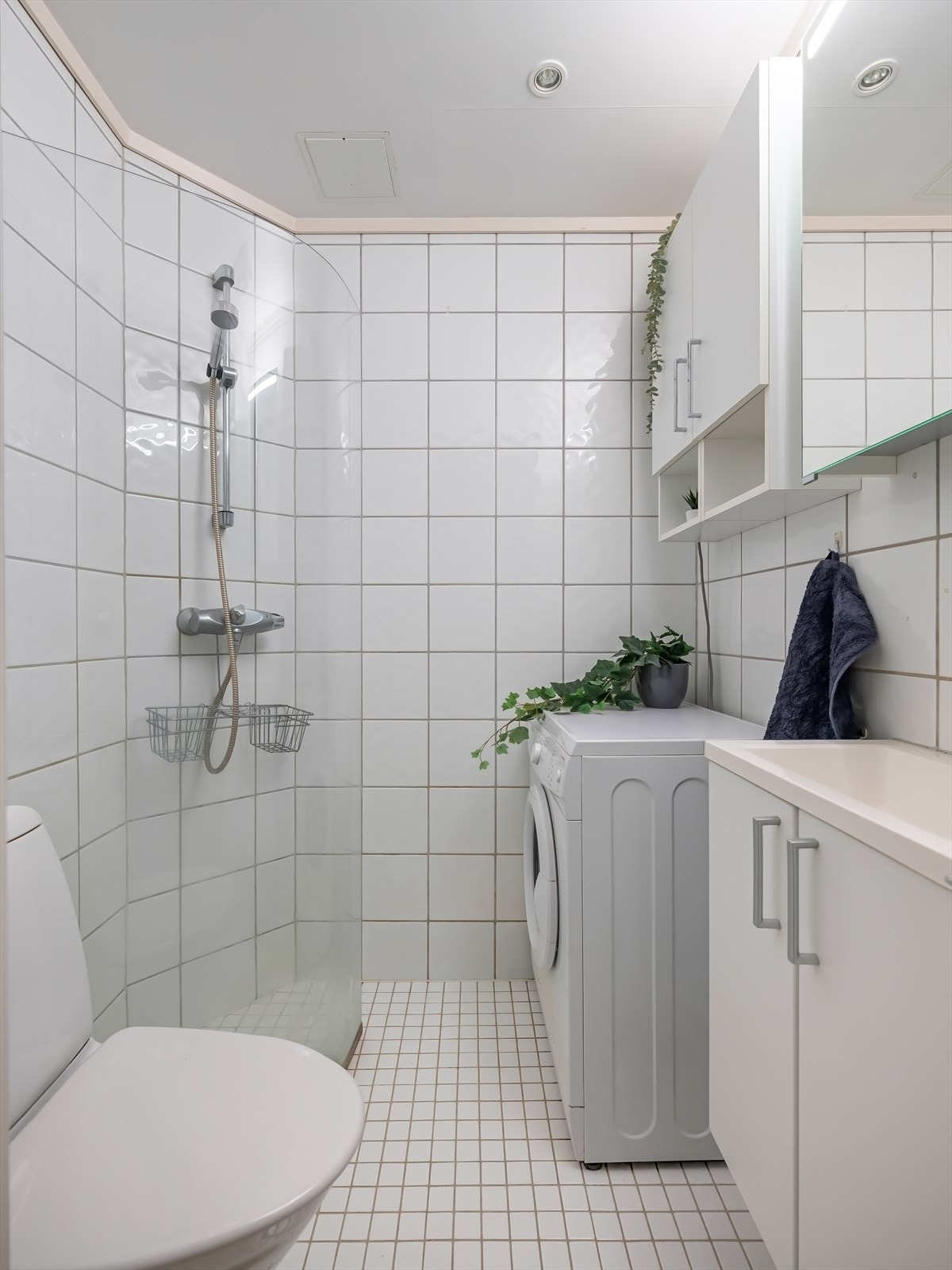 Bad med flislagte overflater, downlights og opplegg for vaskemaskin. Galleribilde