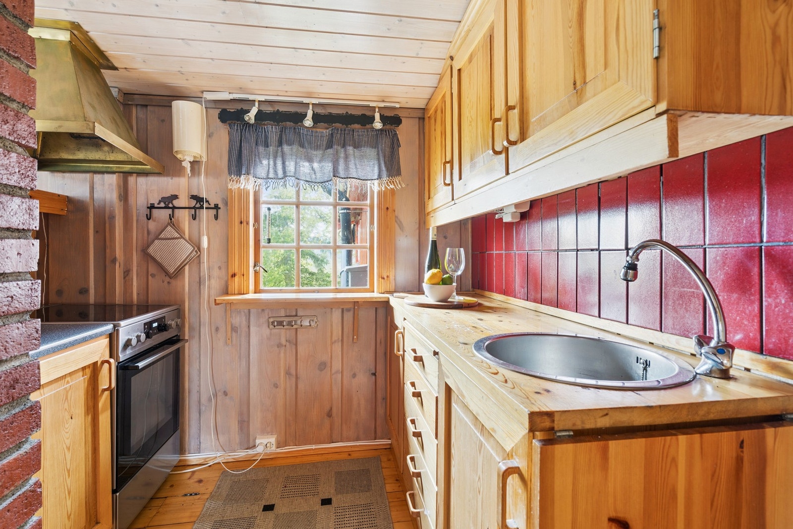 Kjøkkenet har innredning med profilerte fronter. Benkeplaten er av heltre. Det er komfyr. Galleribilde