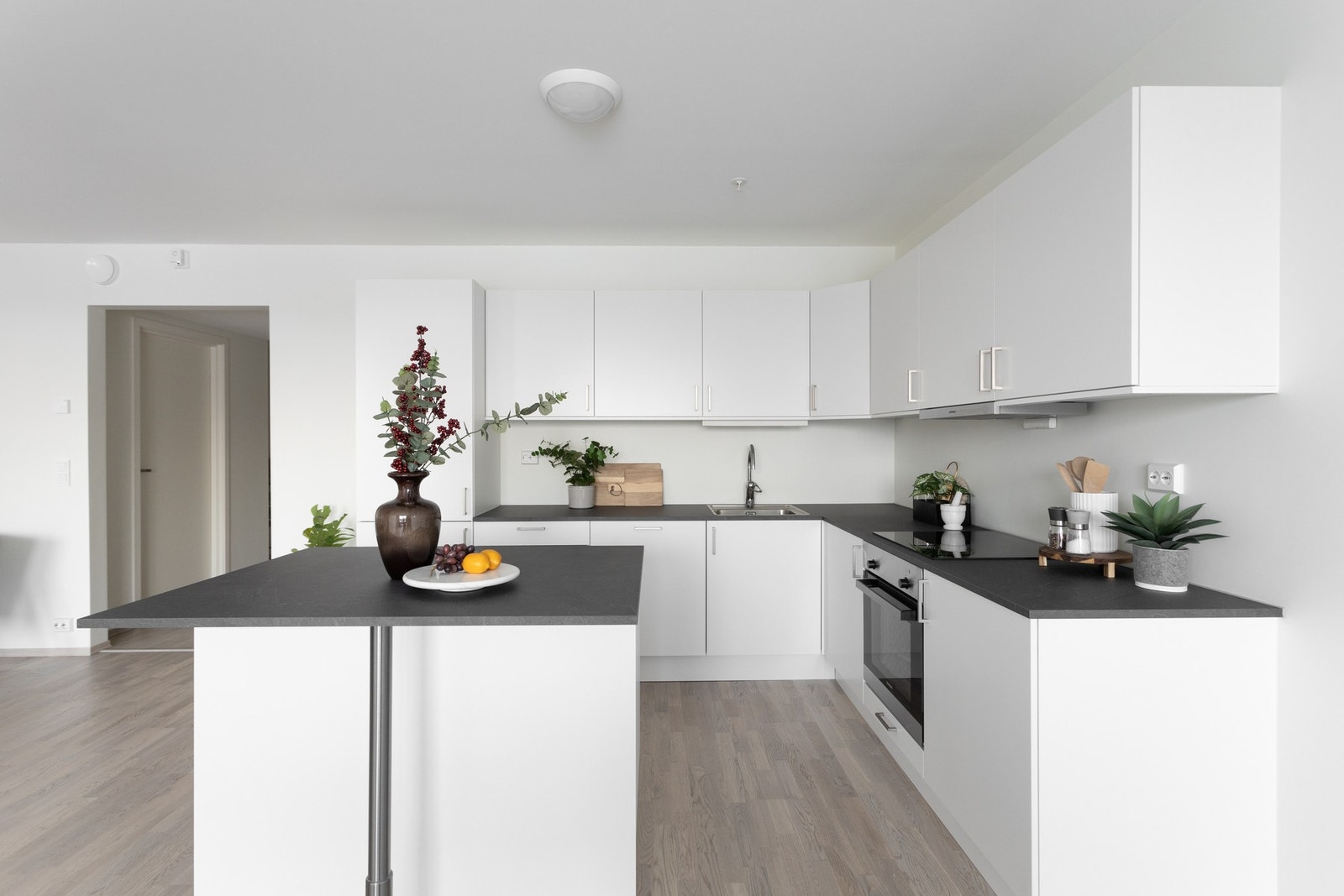 Stilren kjøkkeninnredning med integrert platetopp, stekeovn, oppvaskmaskin og kjøl-/fryseskap Galleribilde