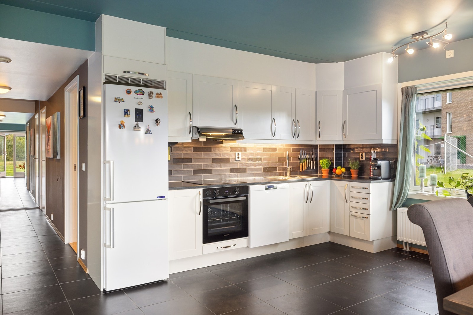 Kjøkkenet har glatte, hvite fronter og integrerte hvitevarer. Galleribilde