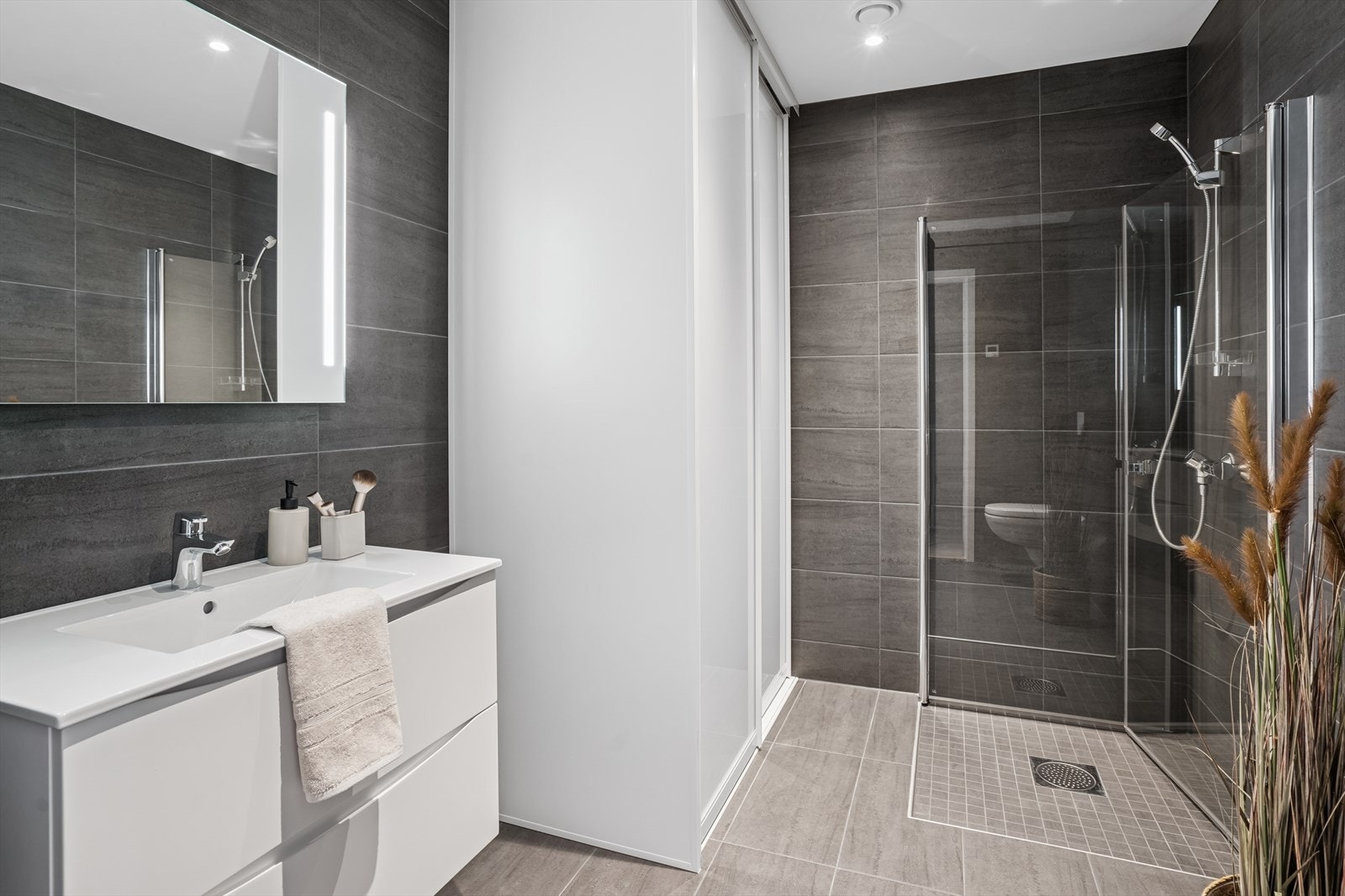 Det første badet har vegghengt klosett, dusj med innfellbare vegger, servant med speil over. Galleribilde