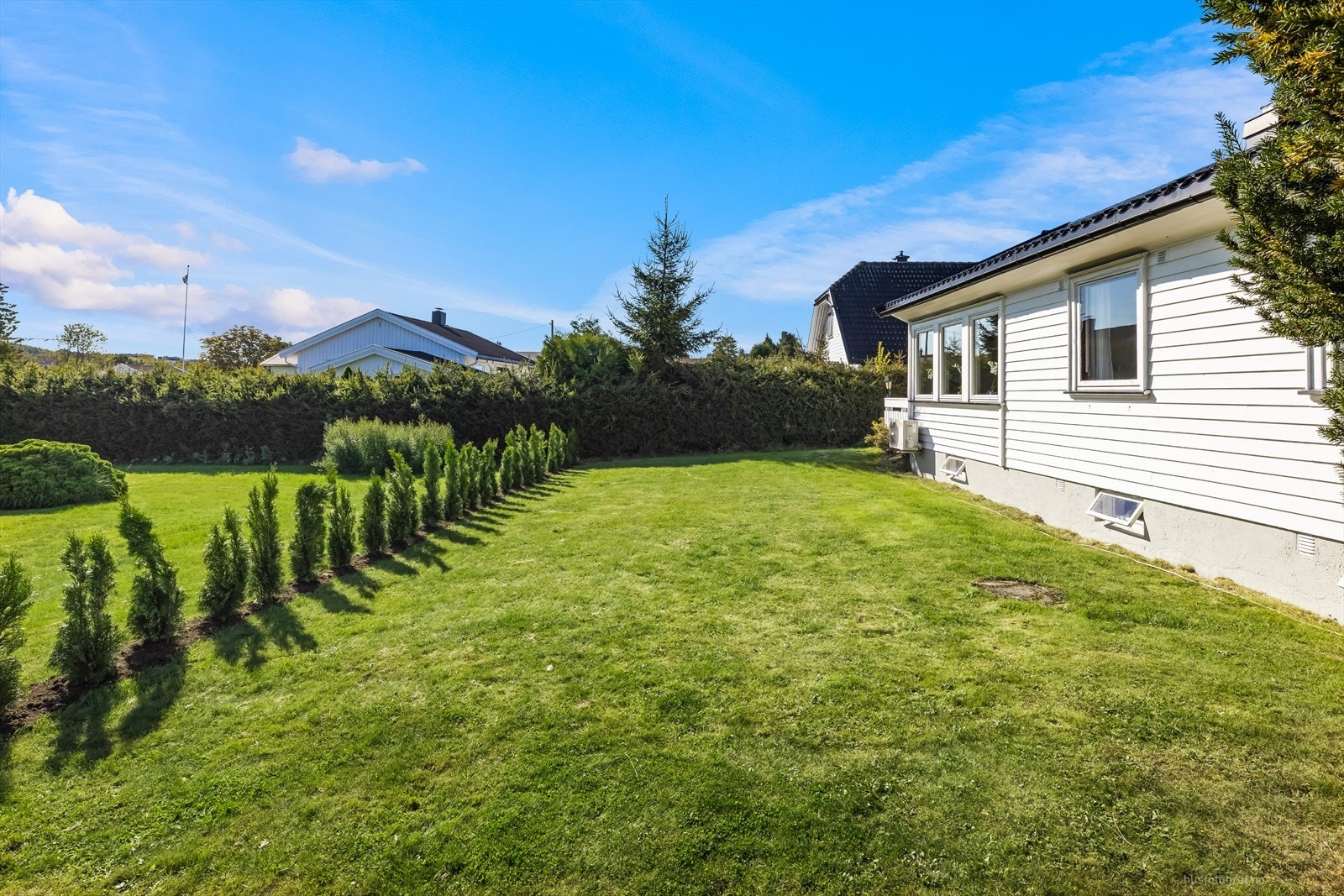 Tomten er beplantet med busker og gressplen. Her er det god plass til hele familien. Galleribilde