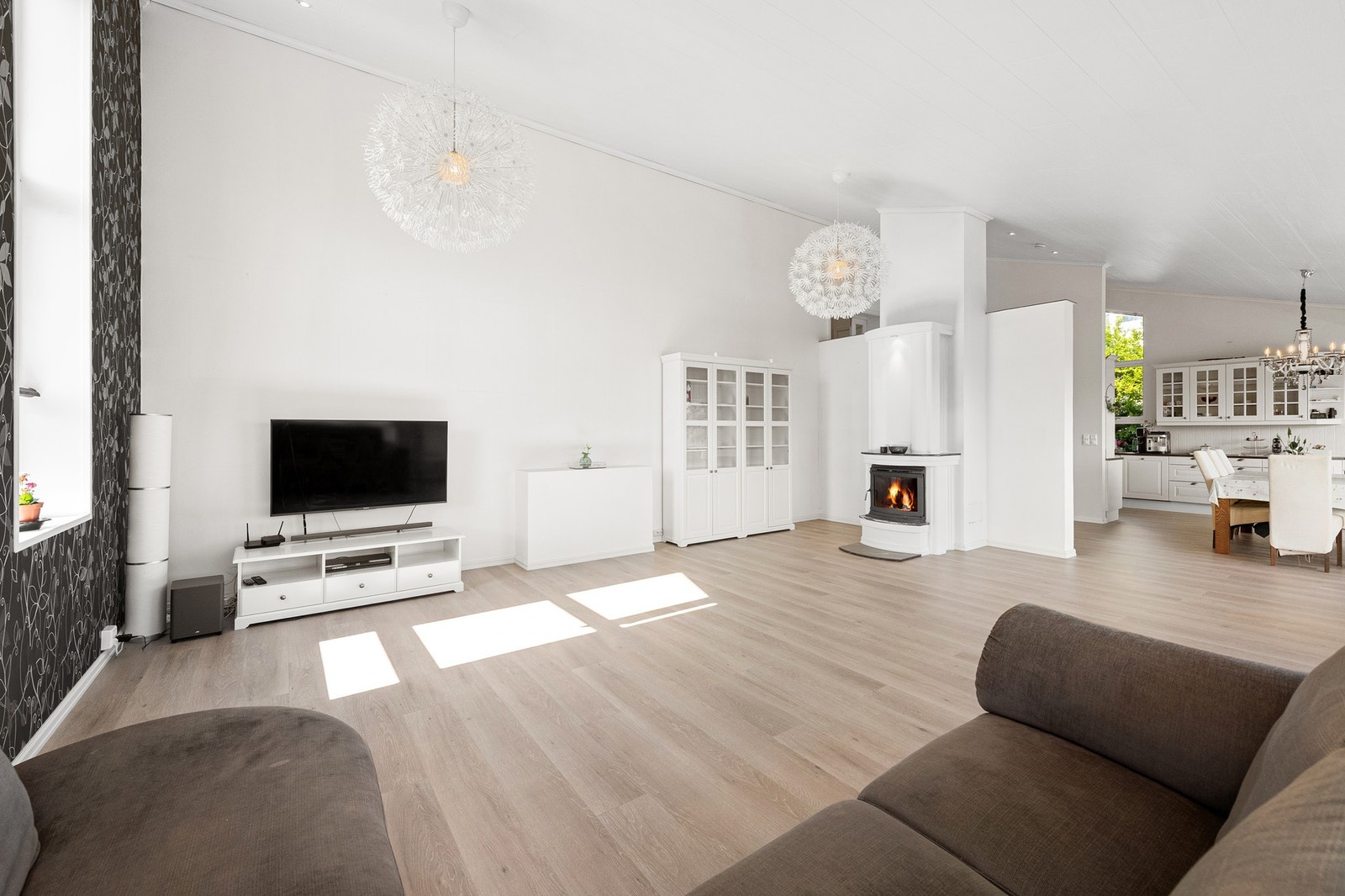 God plass i stua med vedovn og åpen løsning mot kjøkken. Galleribilde