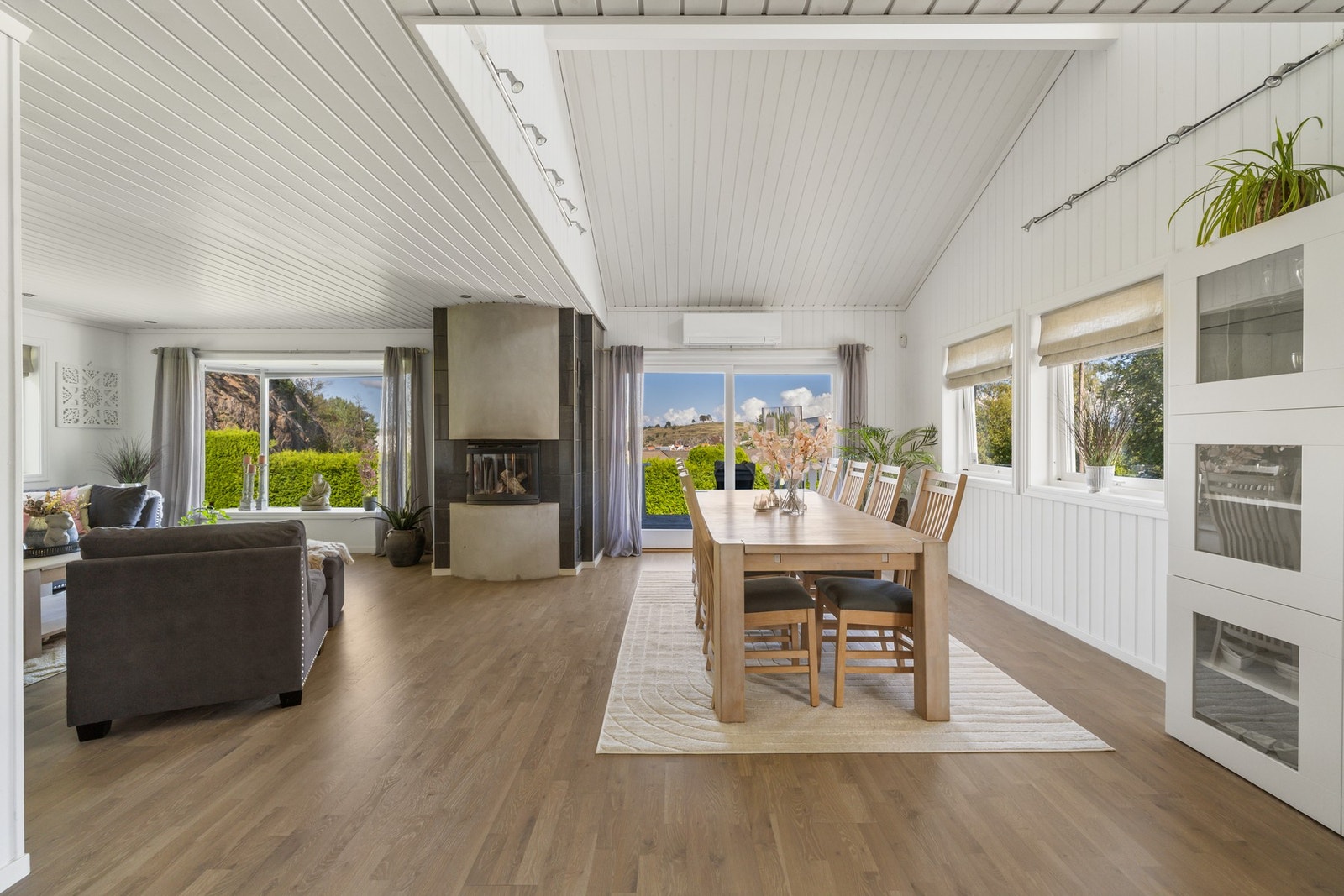 Allrommet er holdt i en stilren kombinasjon med hvitmalte overflater mot gyllent parkettgulv, og det er flott takhøyde over spisestuesonen. Galleribilde