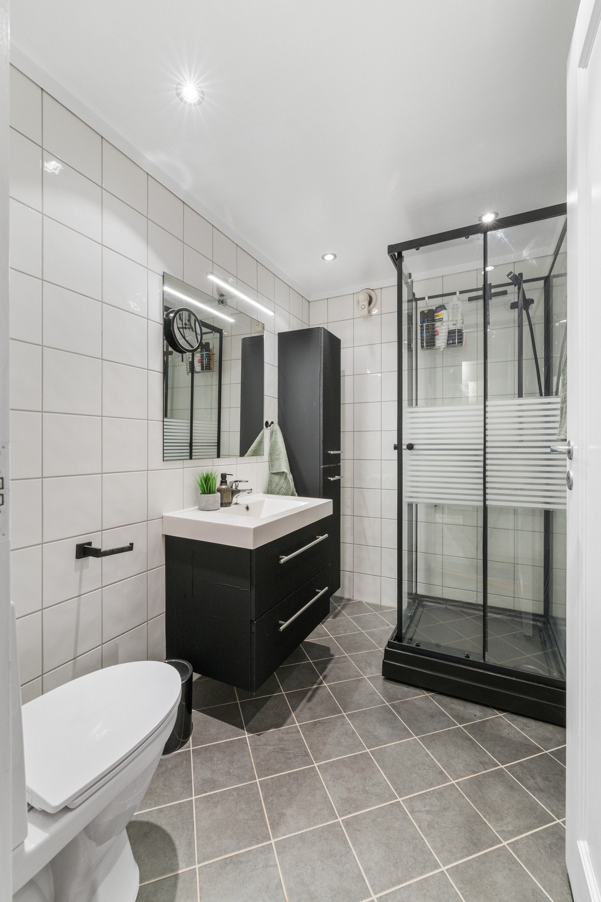 Badet i underetasjen har hvite fliser på veggene, downlights i himlingen og grå fliser på gulv med gulvvarme. Galleribilde