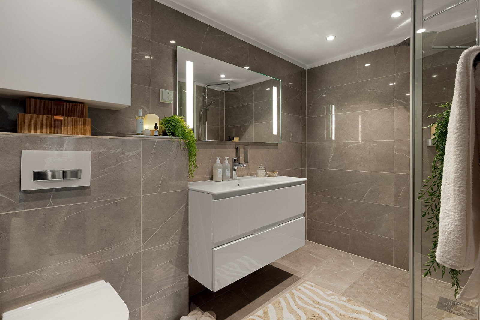 Lekkert bad, hvor moderne løsninger møter tidløs eleganse. Badet er opprinnelig fra byggeåret, men ble i 2016 oppgradert med flis på flis. Galleribilde