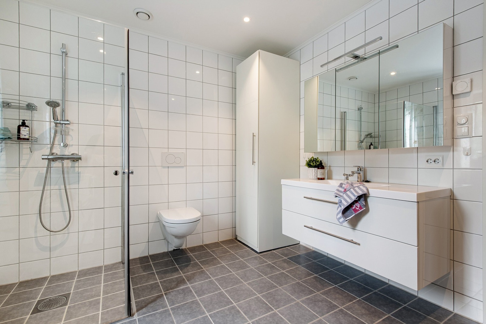 Delikat, flislagt bad med dusjnisje og opplegg for vaskemaskin Galleribilde