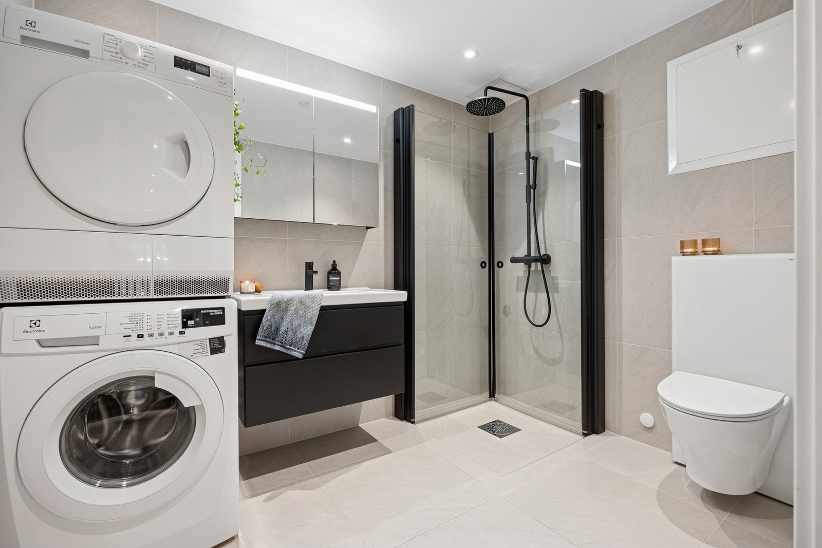 Lekkert og delikat baderom med store fliser og elegante detaljer. Er blant annet hyller i dusjen for ryddig utrykk i dusjhjørnet. Galleribilde