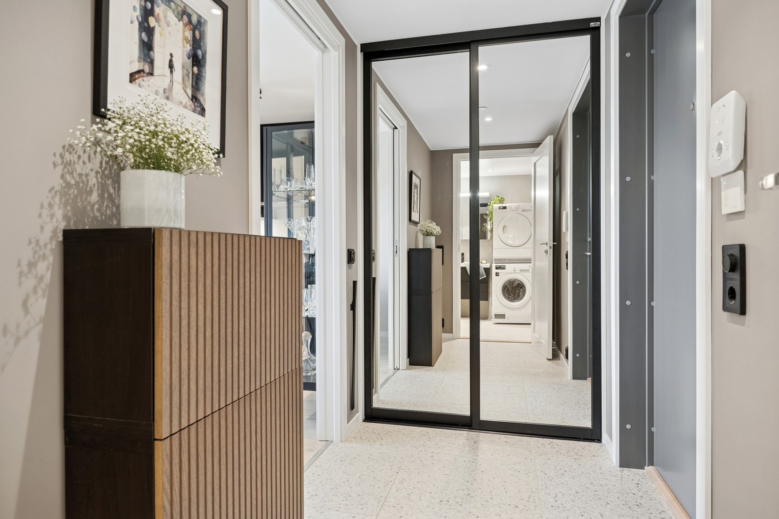Flislagt entré gir et eksklusivt inntrykk. Her ønskes man velkommen inn til en lys og innbydende entré med skyvedørsgarderobe. Galleribilde