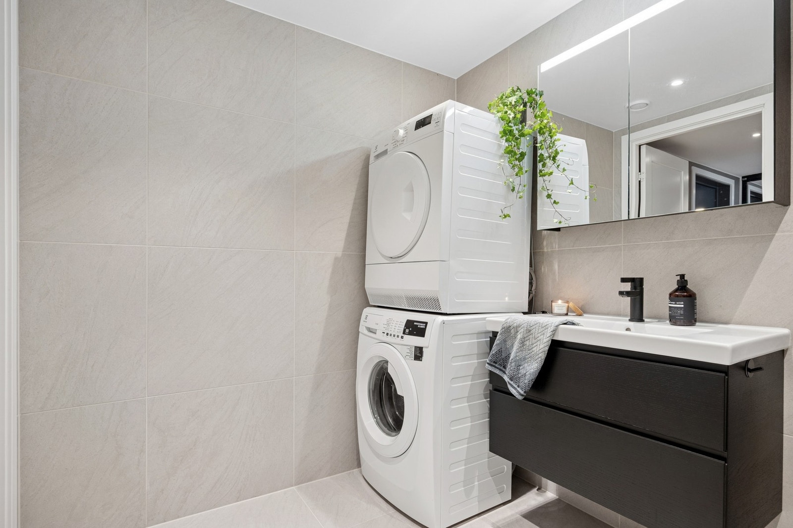 Badet er utstyrt med servantinnredning, speilskap, dusjhjørne med innfellbare dusjdører og vegghengt toalett, samt opplegg for vaskemaskin. Galleribilde