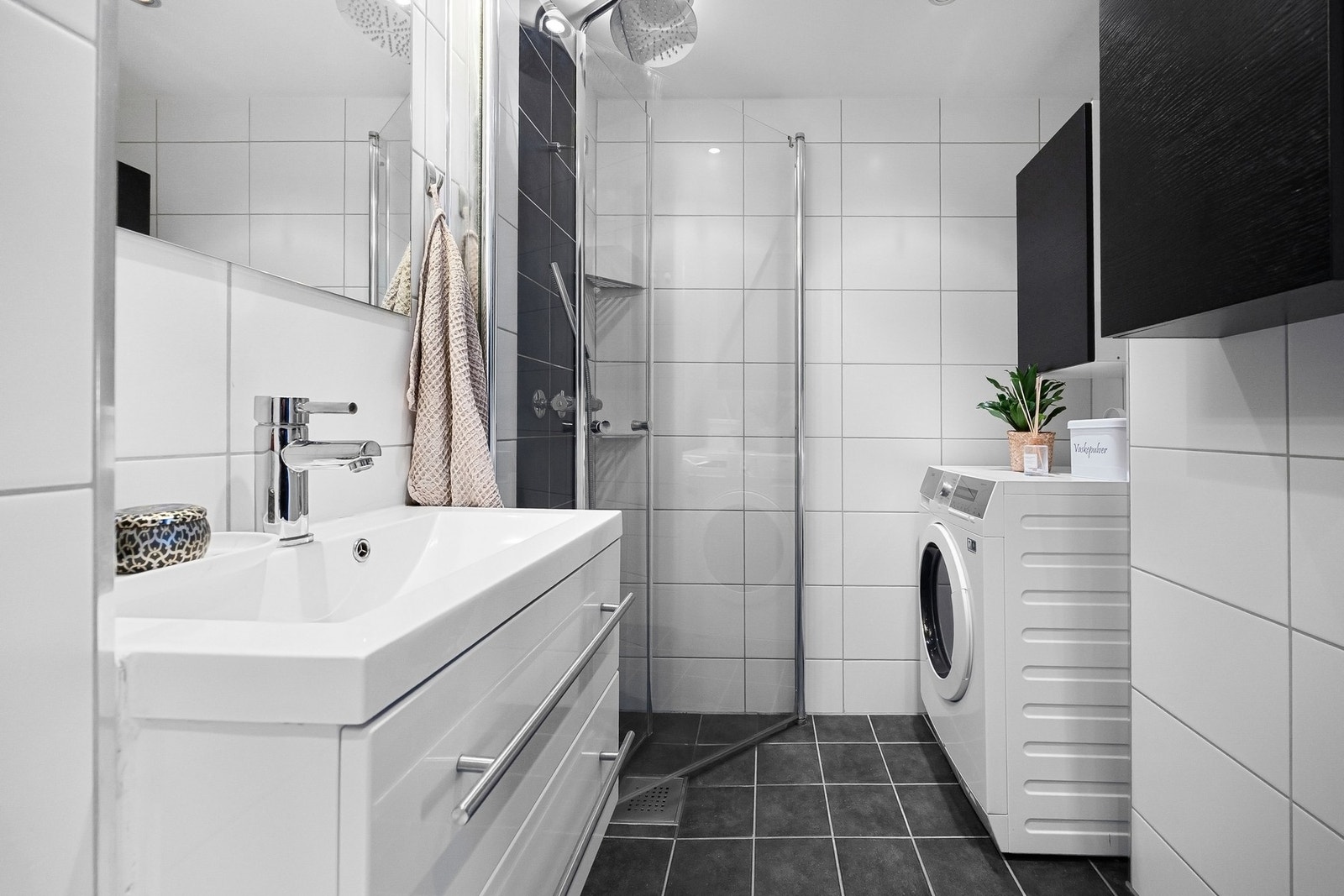 Pent, flislagt bad med varmekabler, servant med underskap og speil, veggmontert toalett og dusjhjørne. Galleribilde