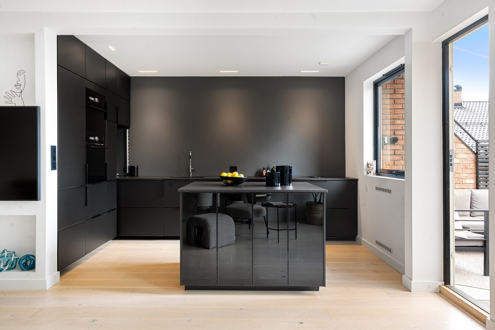 Stilrent og moderne kjøkken av god kvalitet med kjøkkenøy, sømløse overganger og tidløse materialer. Lekker innredning fra 2019 med sorte, glatte fronter og keramisk benkeplate (Dekton). Underlimt oppvaskkum og ettgreps armatur fra Tapwell. Galleribilde