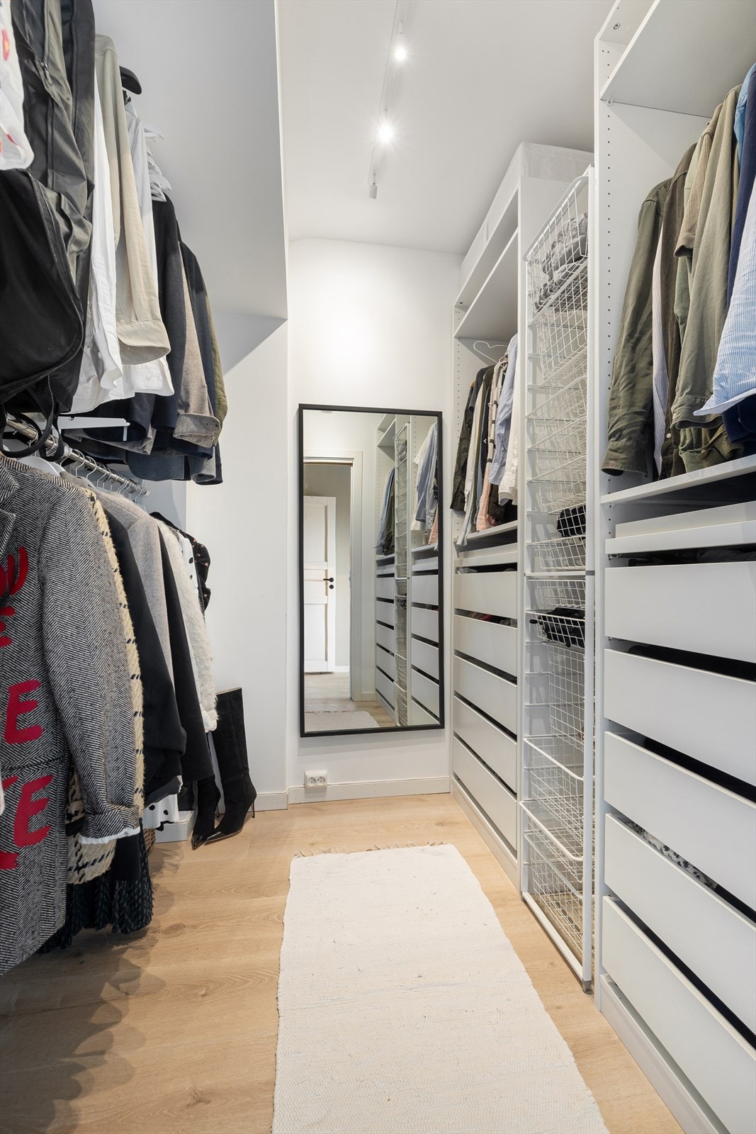 Her får du svært god oppbevaringsplass, med en praktisk åpen garderobeløsning langs den ene veggen og garderobestenger som utnytter plassen effektivt på motsatt side. Galleribilde