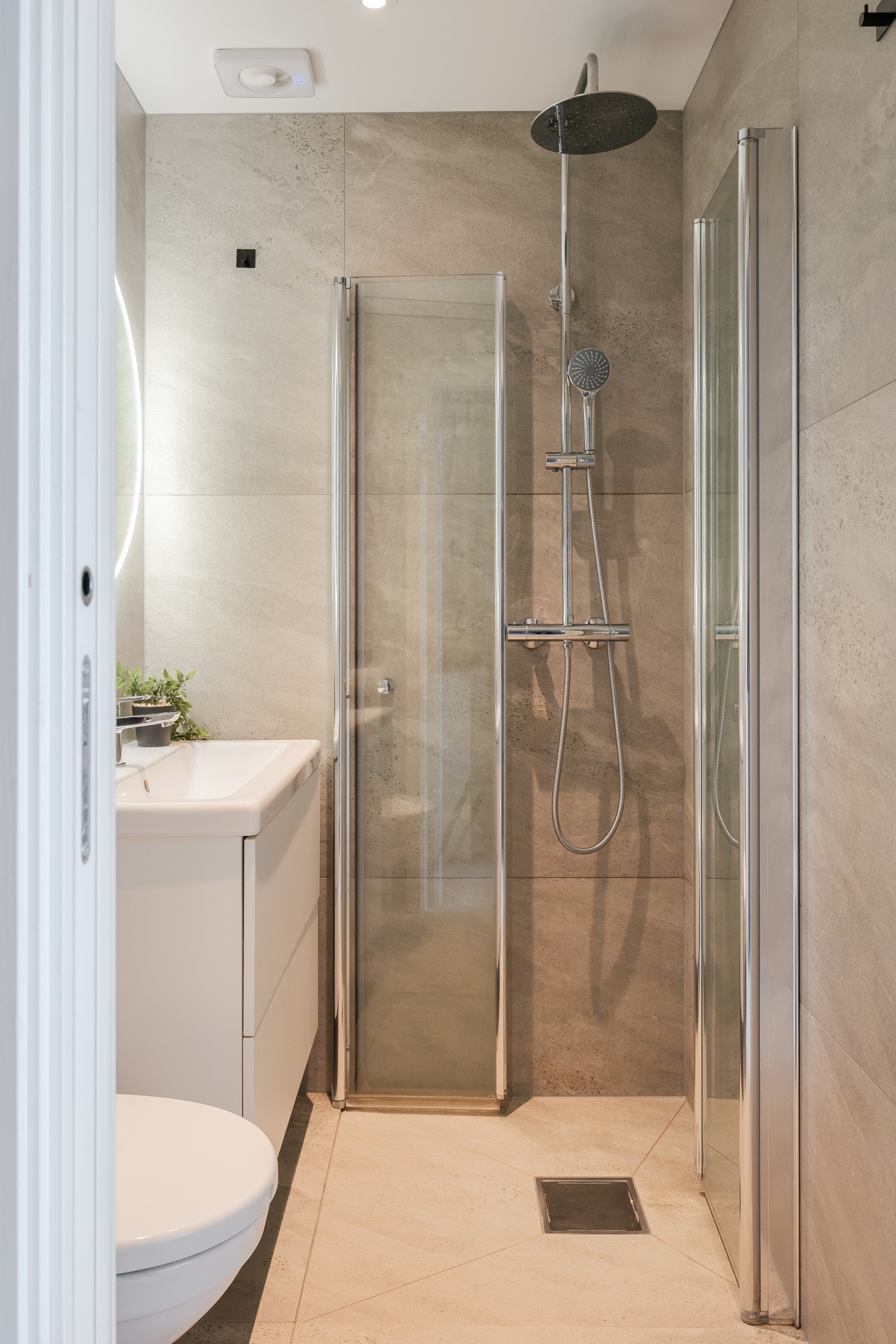 Badet har dusjvegger av glass, vegghengt toalett, og innredning med servant. Galleribilde