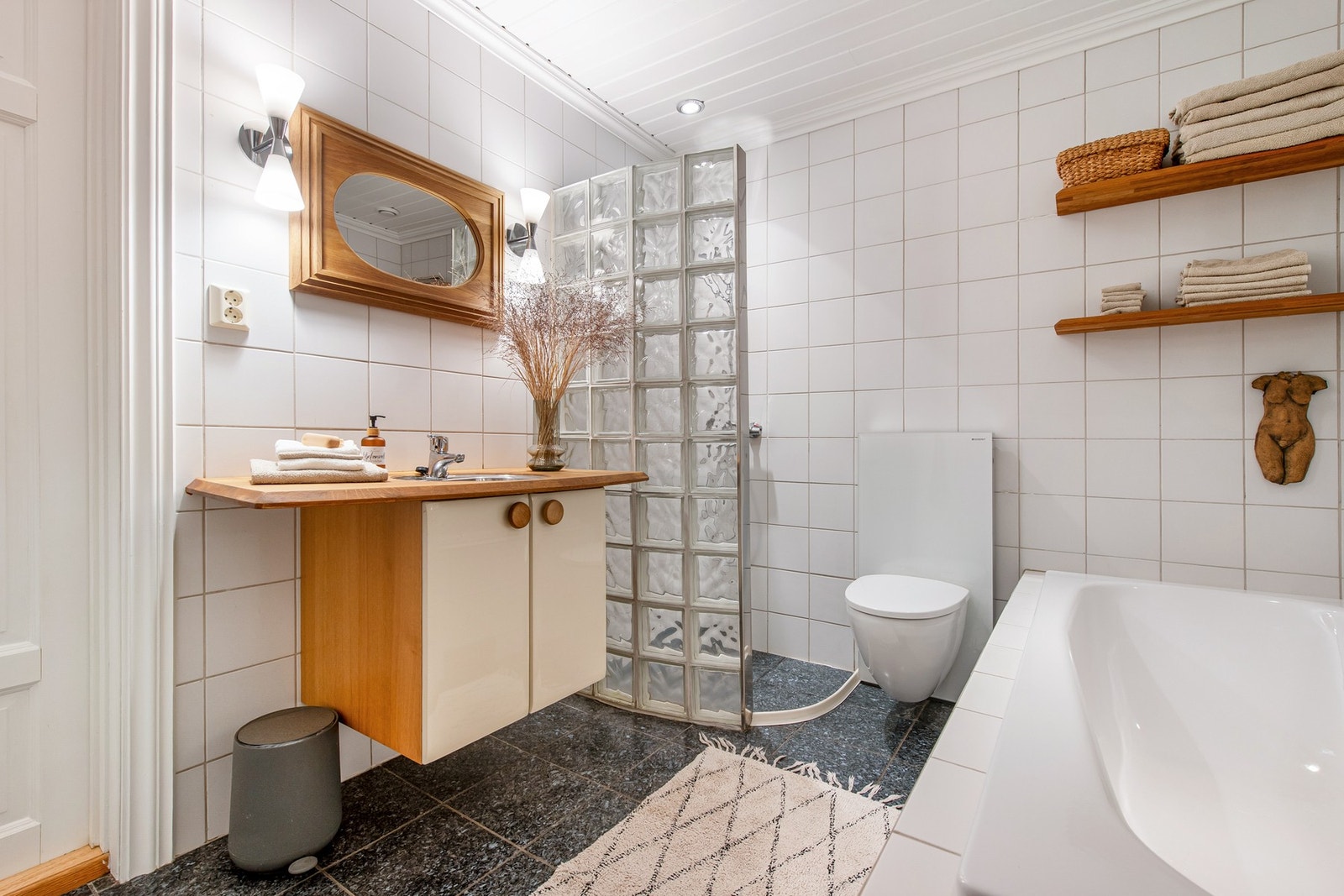 Pent flislagt bad i 1. etasje. Larvikittfliser på gulvet. Rommet inneholder: Dusjnisje, badekar, toalett og servant. Galleribilde