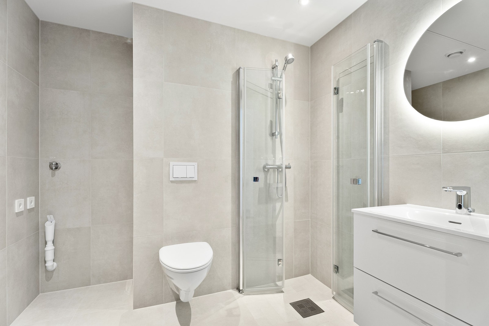 Delikat flislagt bad med opplegg for vaskemaskin, dusjhjørne, wc og servant med god oppbevaringsplass i skuffer Galleribilde