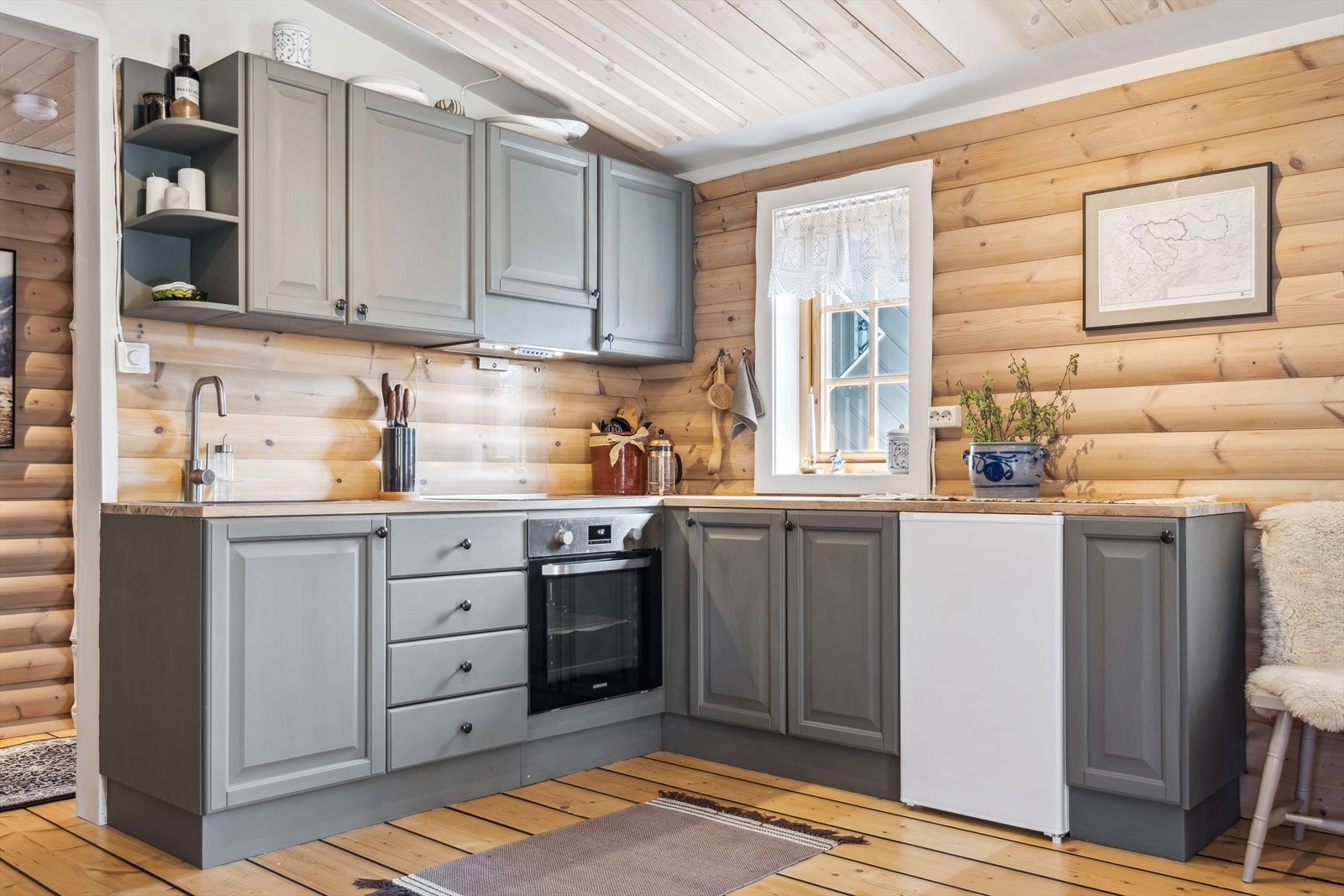 Kjøkkenet er modernisert med malte overflater og integrert komfyr og platetopp. Benkekjøleskap til høyre. Galleribilde