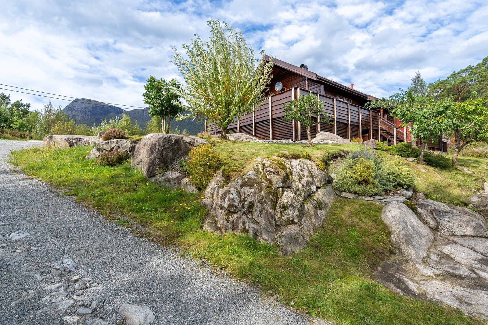 Hytten sett nedenfra opp mot opparbeodet område med beplantning og trær Galleribilde