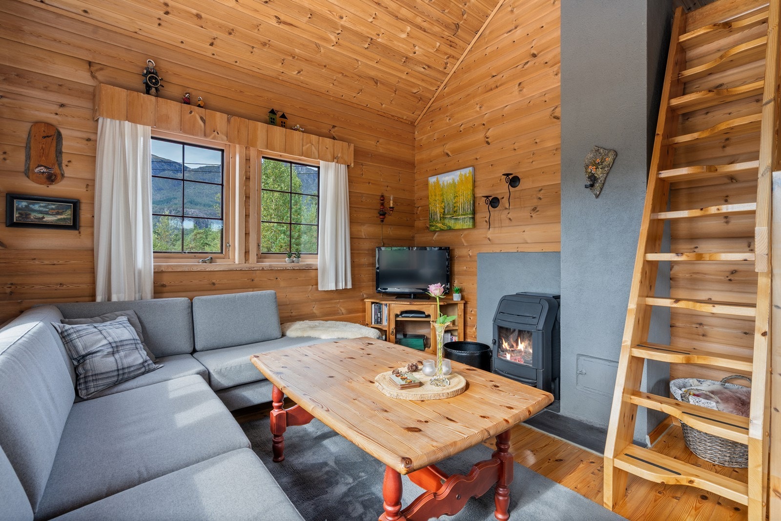 I stuen er det en peisovn og samba trapp opp til hems Galleribilde